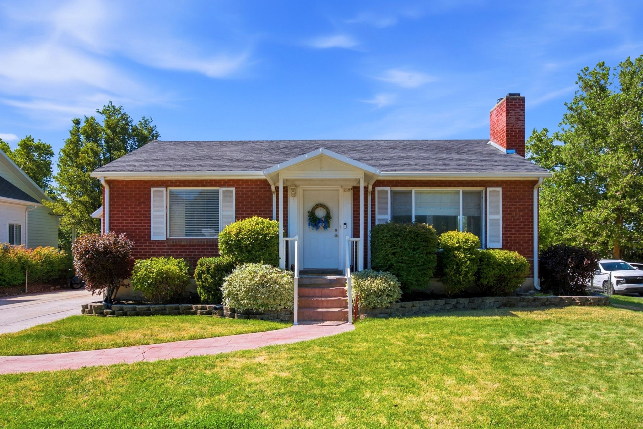 Brick exterior residence featuring a gabled roof and a prominent brick chimney
