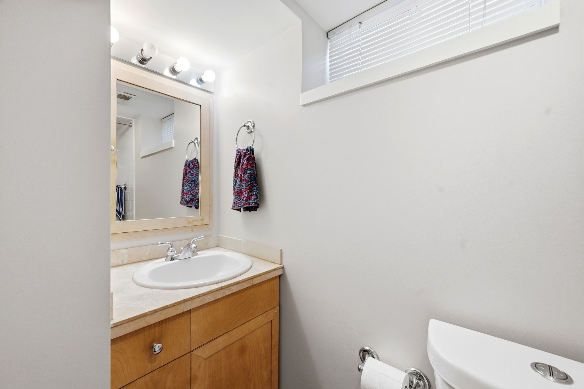 Bathroom vanity featuring a light wood cabinet, integrated sink, and a light-toned countertop