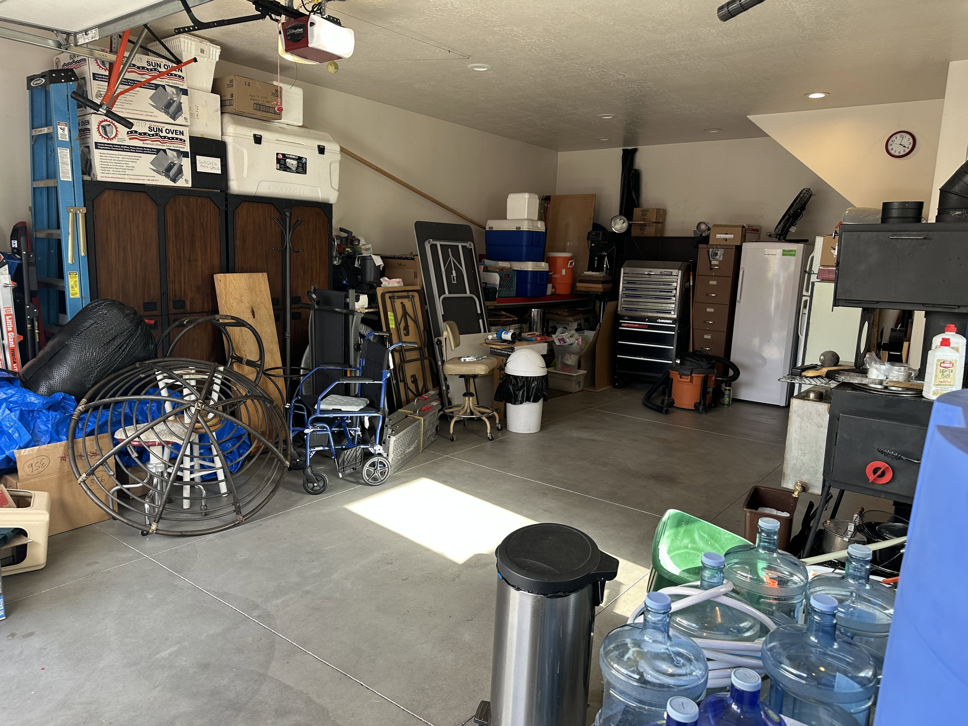 Spacious garage featuring a concrete floor, overhead garage door, built-in shelving, wood-burning stove, and recessed lighting