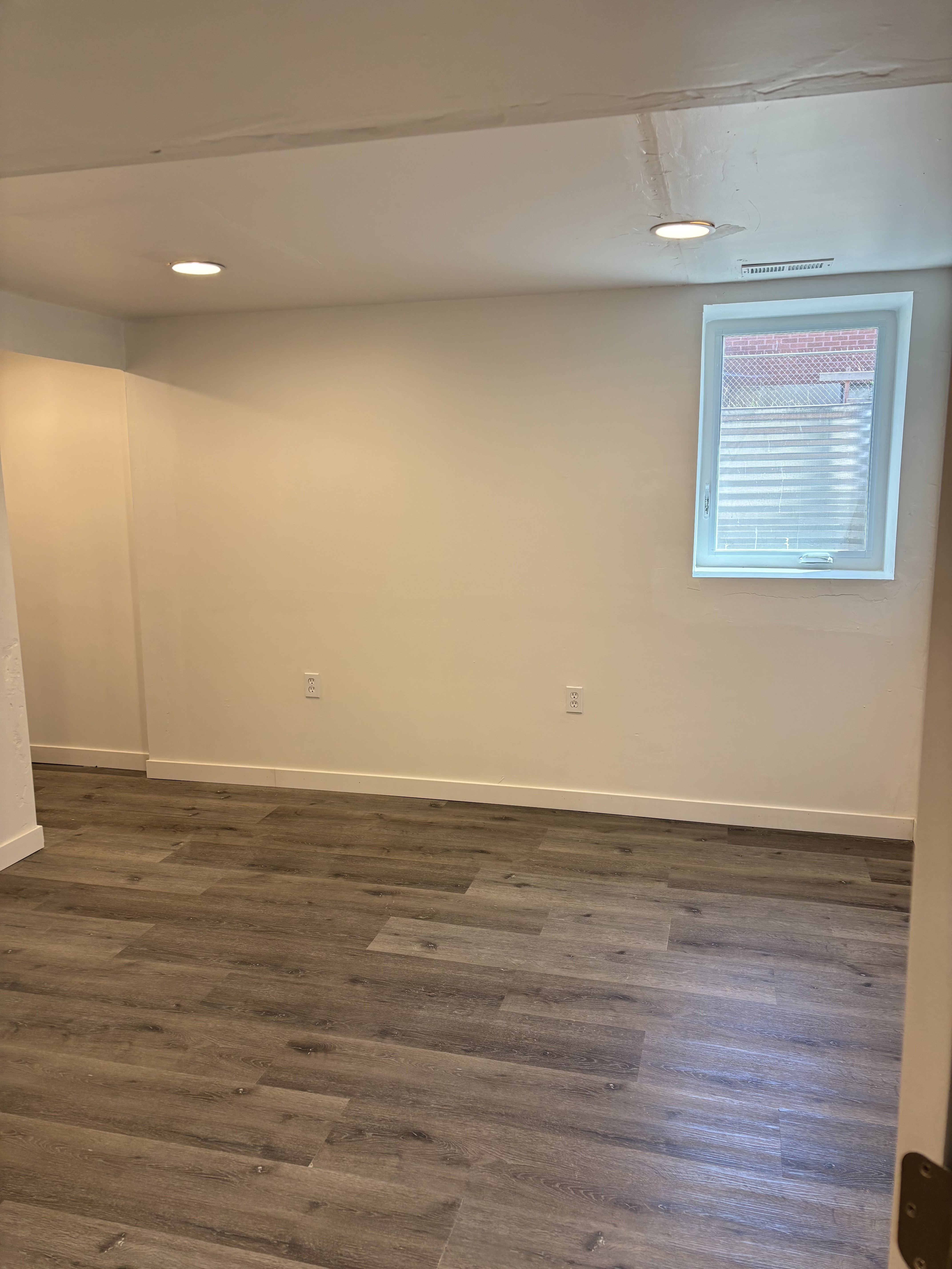 Spacious room featuring wood-finish flooring, recessed lighting, and a white trim baseboard.
