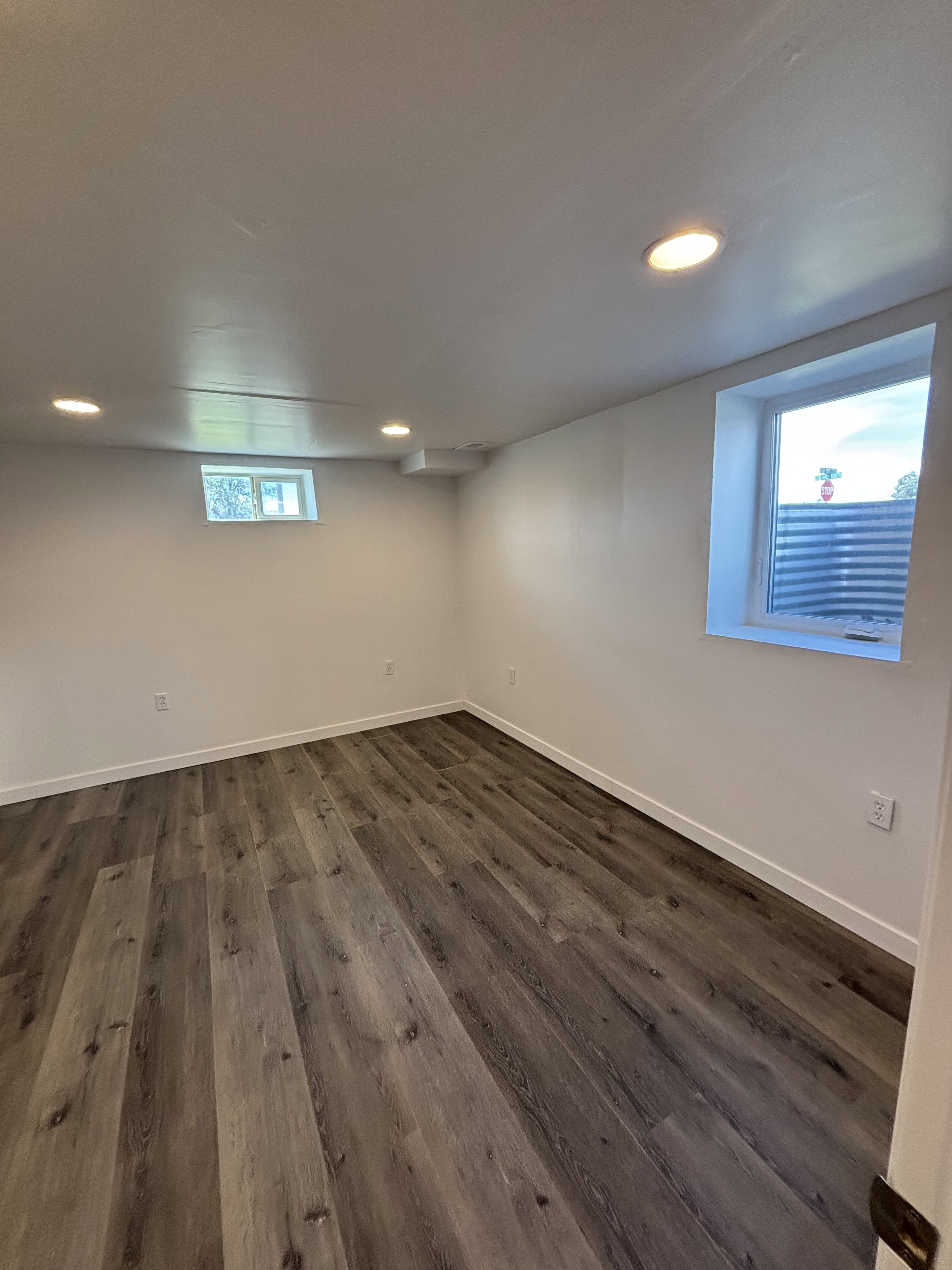 Room featuring wood-finish flooring, recessed lighting, white walls, white baseboards, and two windows.