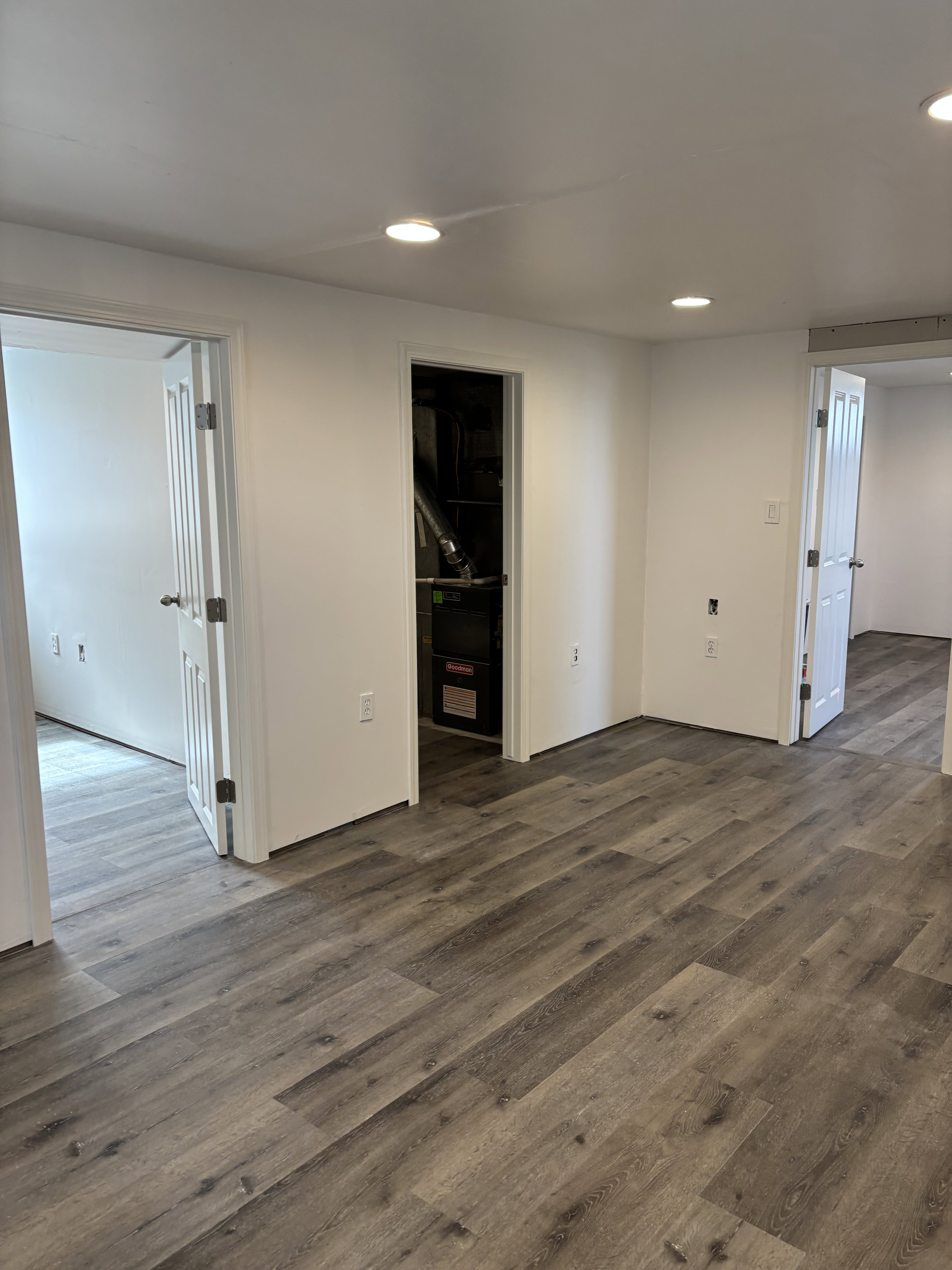 Spacious room featuring wood-finish flooring, white walls, and recessed lighting.
