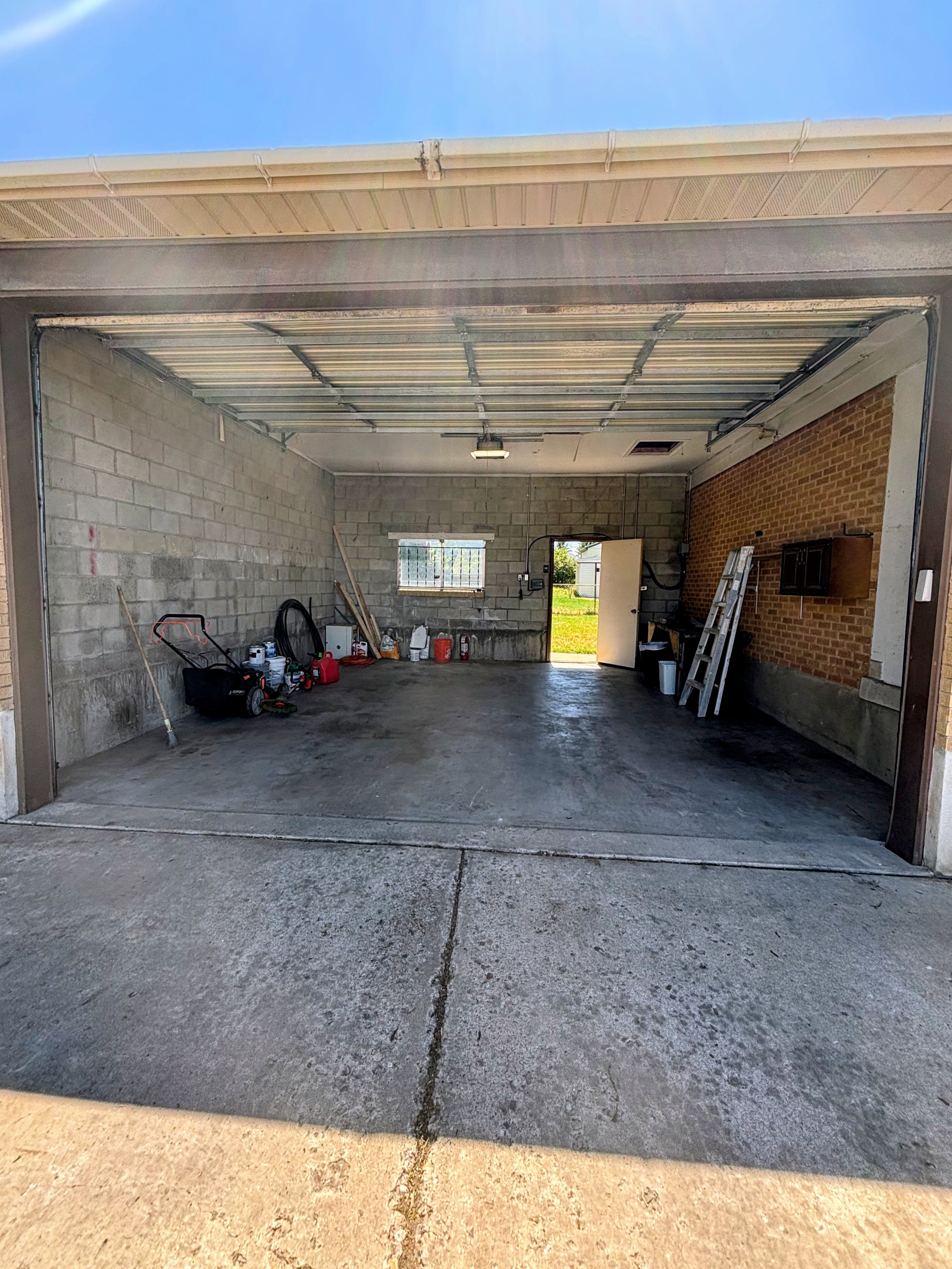 Spacious garage featuring concrete flooring, block wall construction, a single window, and a rear door providing exterior access.