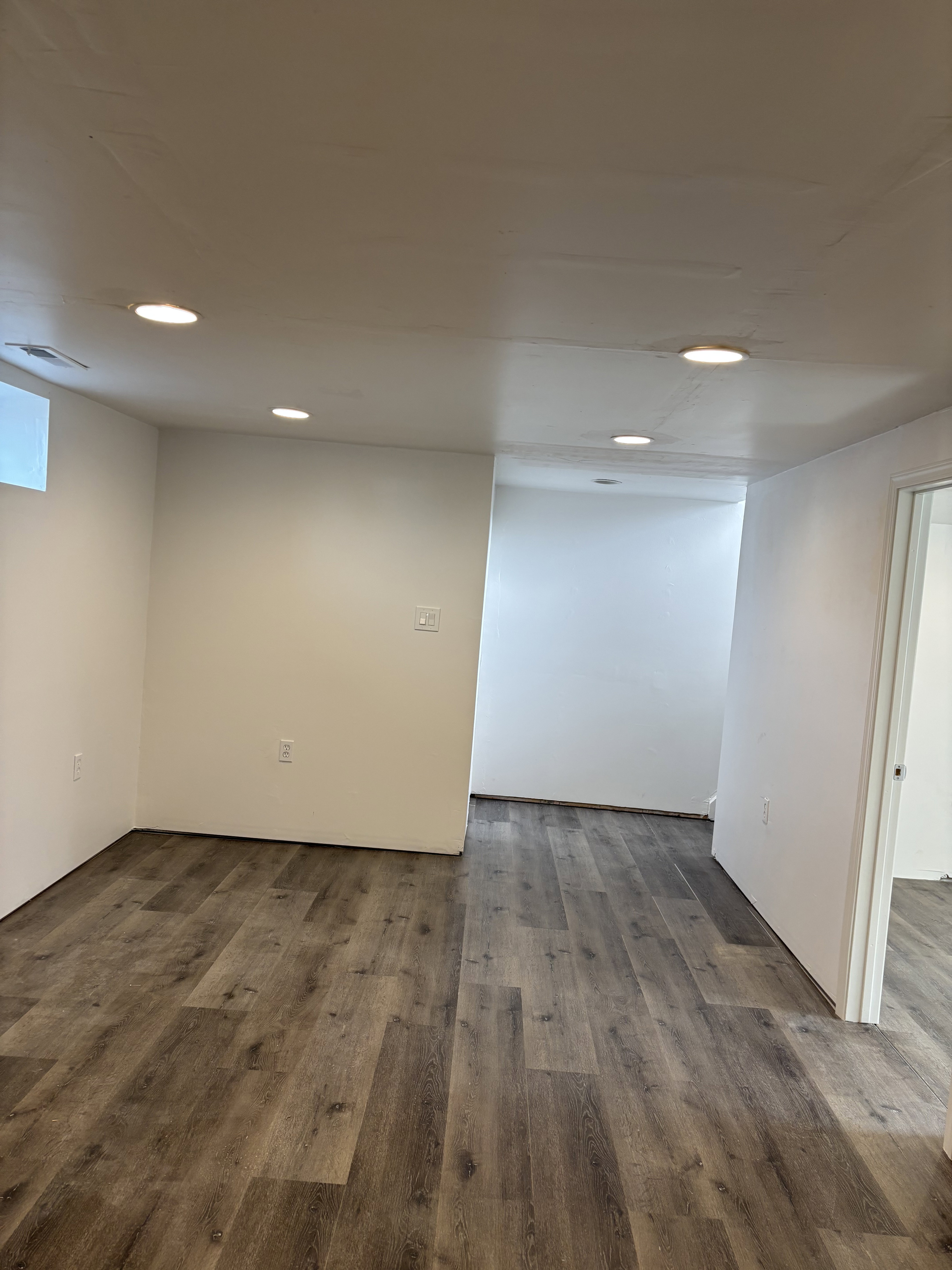 Spacious interior featuring wood-finish flooring, recessed lighting, and bright white walls.