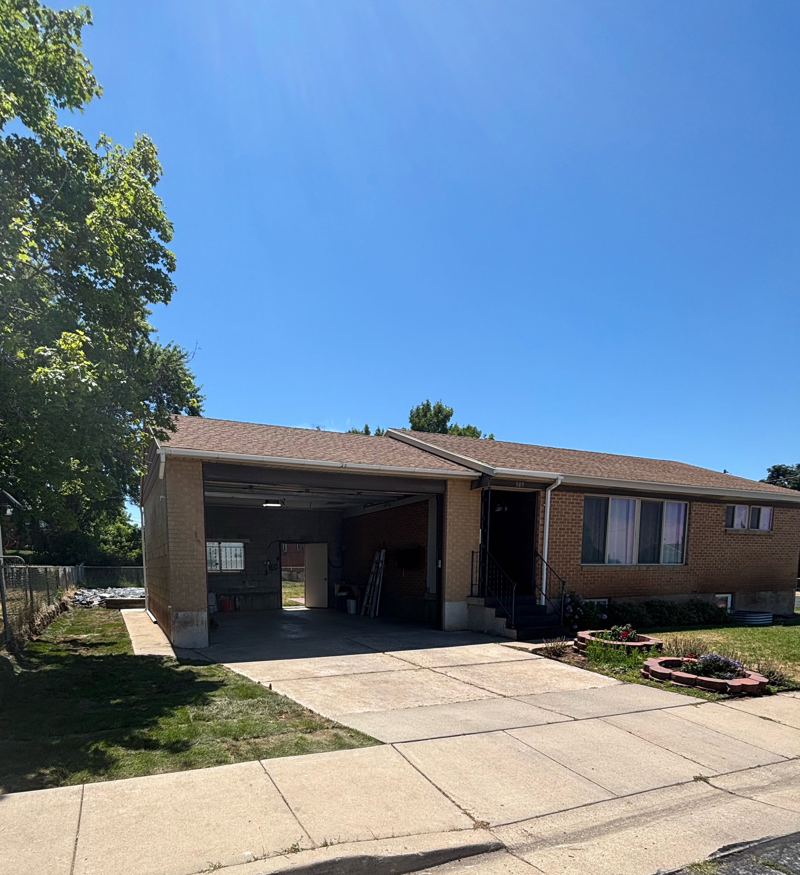Brick exterior residence featuring a garage, concrete driveway, and front entry stairs with a handrail along with side view into backyard.