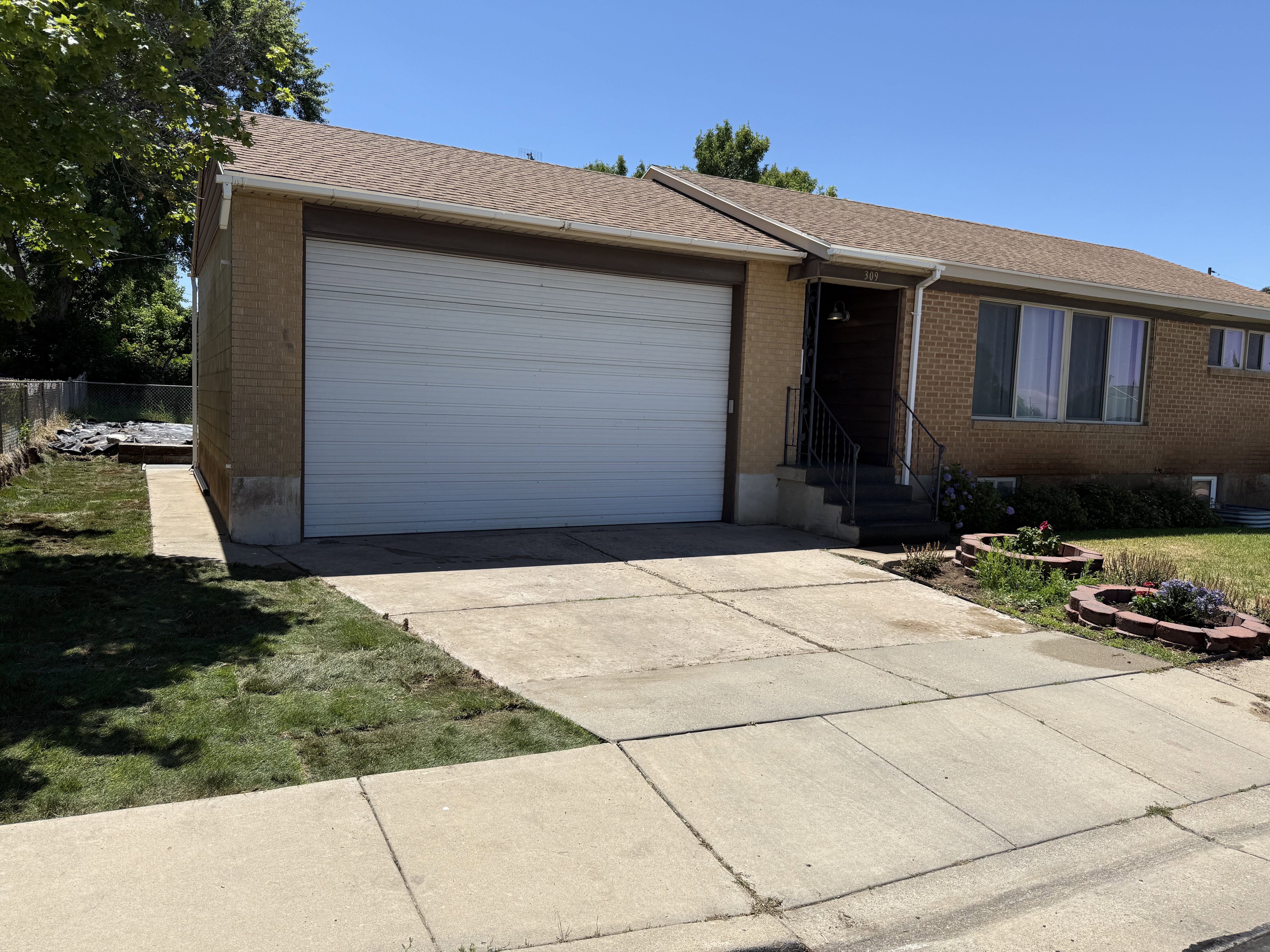 Rambler-Ranch style - Brick exterior with an attached garage, featuring a concrete driveway and sidewalk.