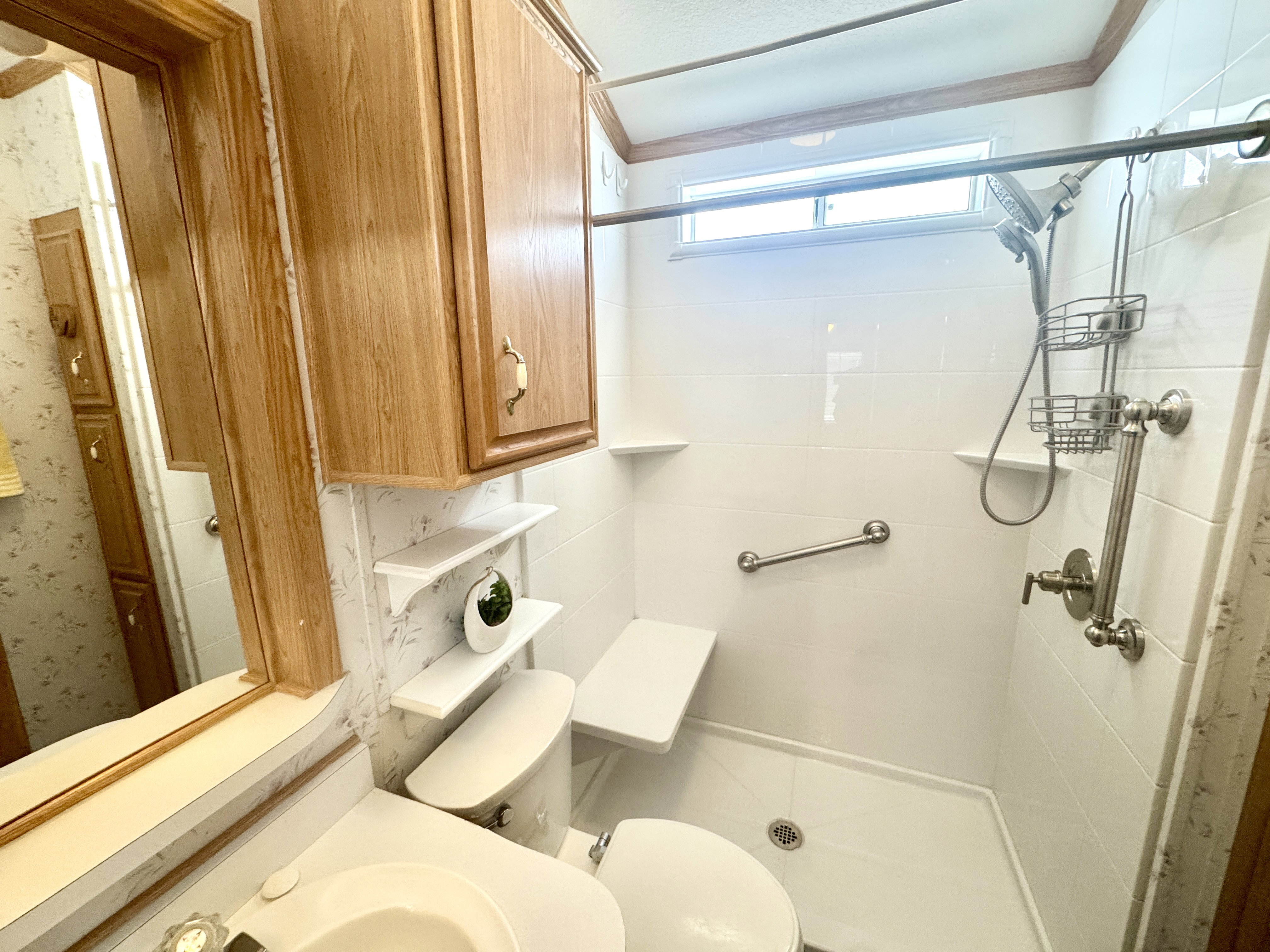 Shower with white tile surround, built-in window, and stainless steel fixtures
