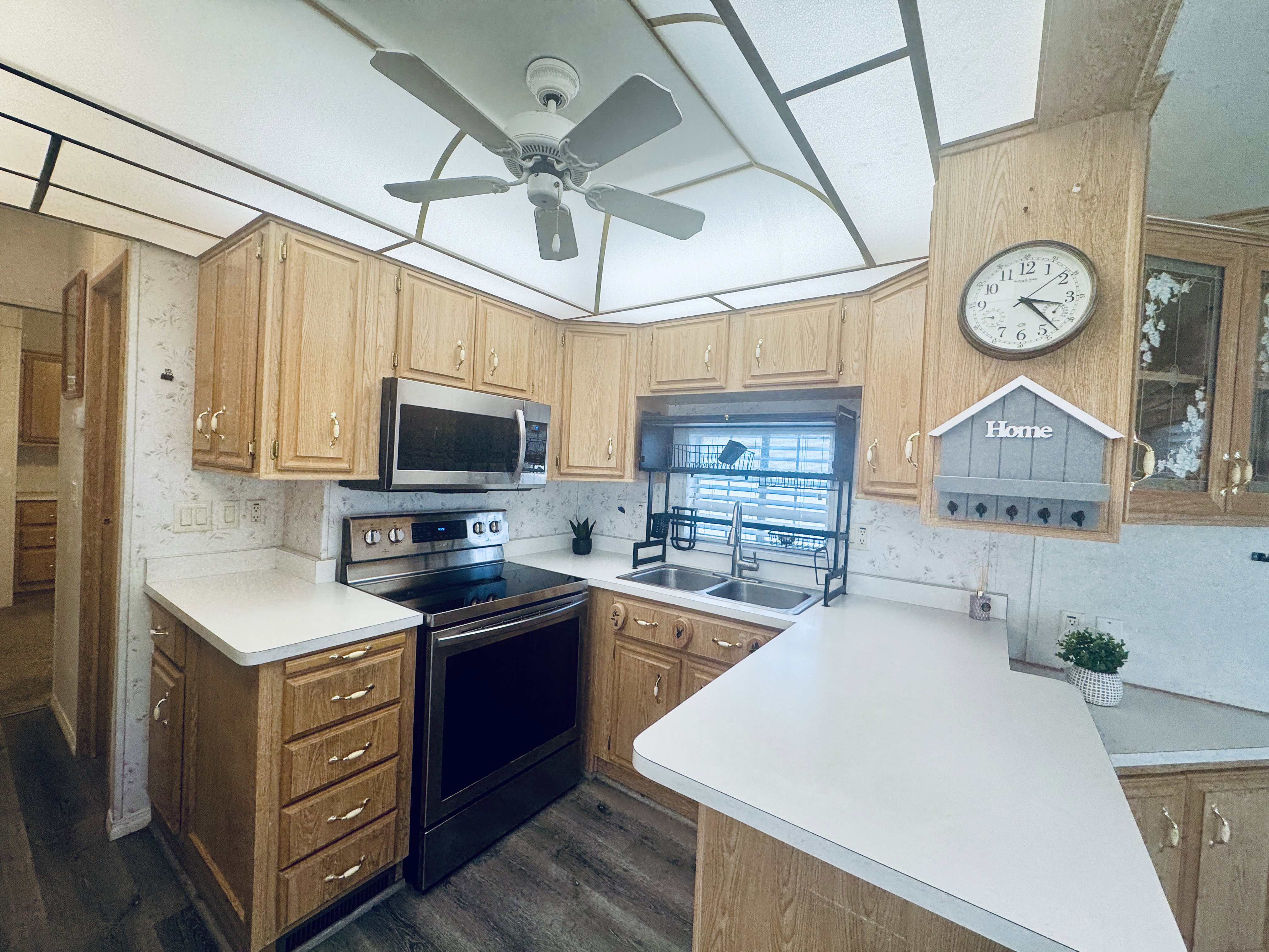 Kitchen featuring wood-finish cabinetry, white countertops, stainless steel appliances, and a double basin sink