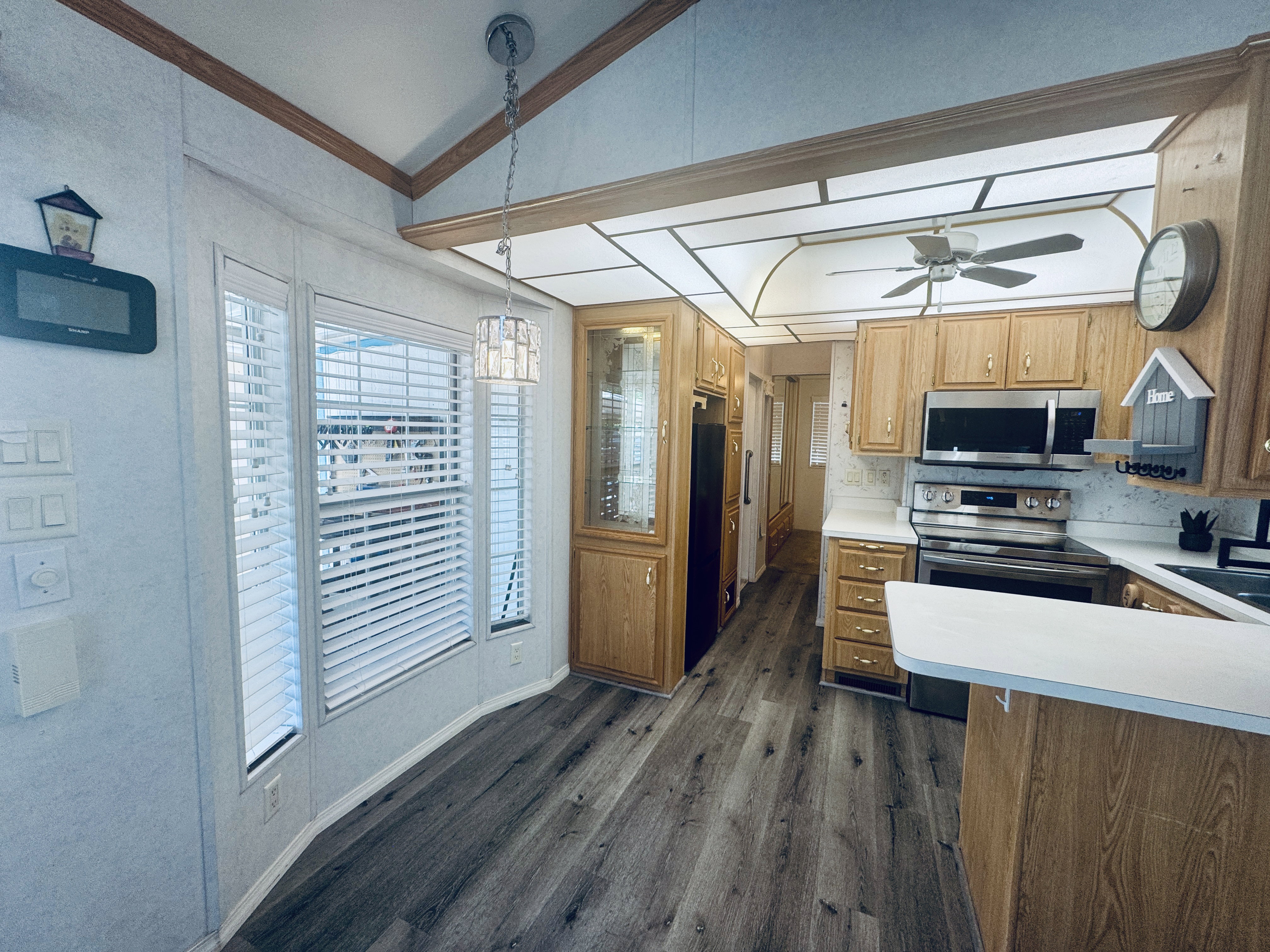 Kitchen featuring wood-finish flooring, oak cabinetry, stainless steel appliances, and an integrated ceiling fan