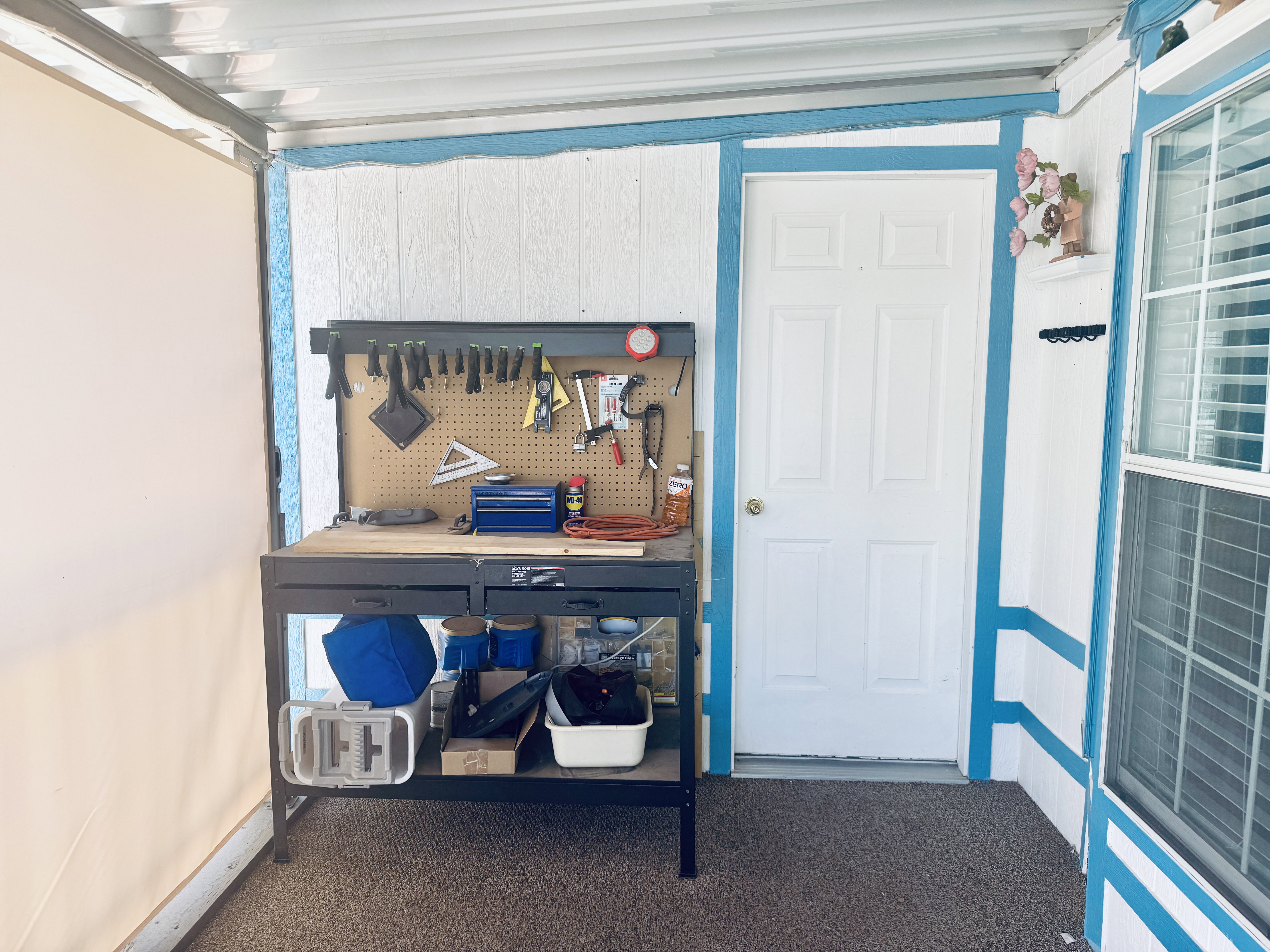 Covered patio area with white siding and blue trim accents
