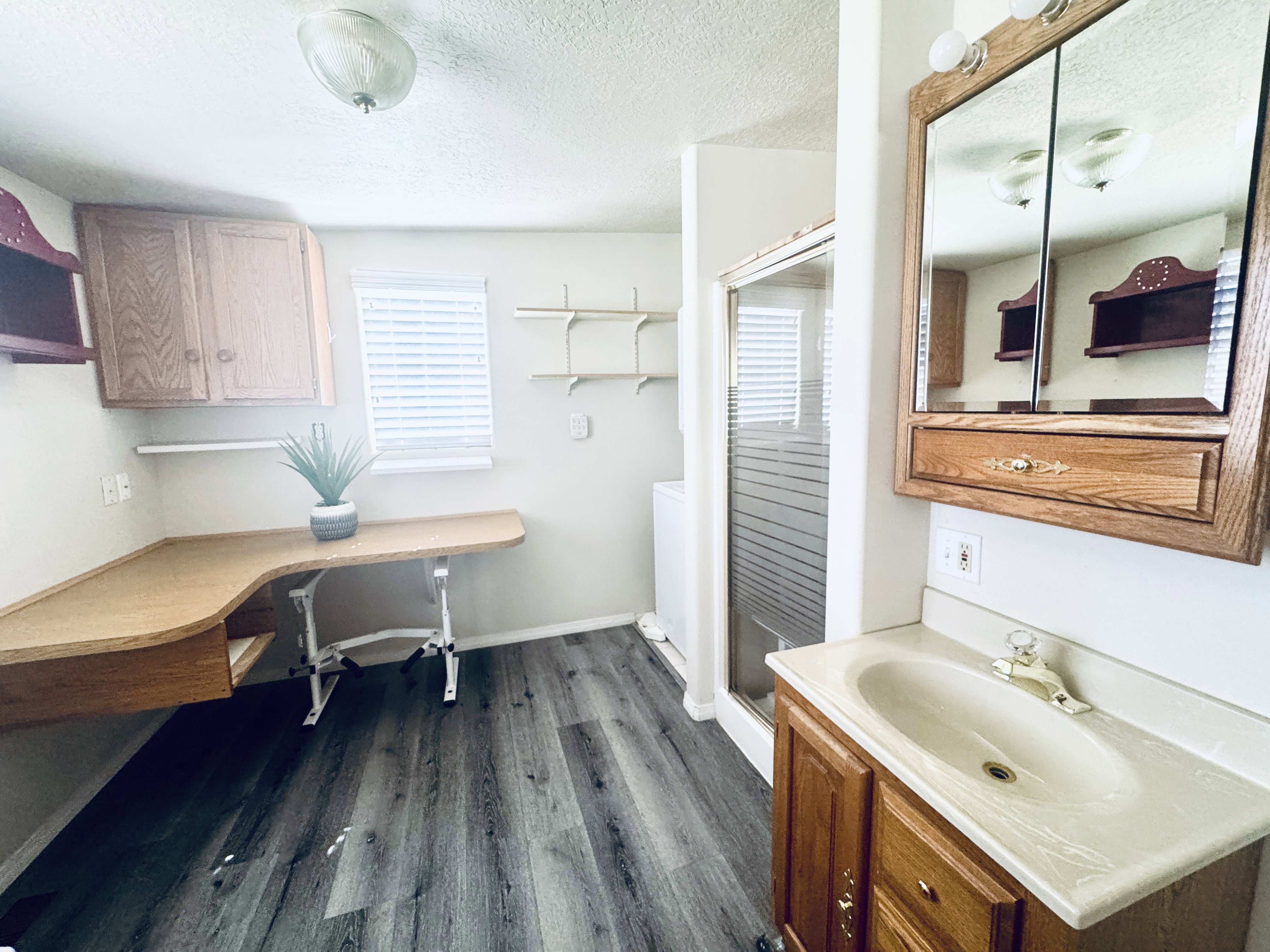 Bathroom featuring a wood-finish vanity with an integrated sink, a mirrored medicine cabinet, and a glass-enclosed shower