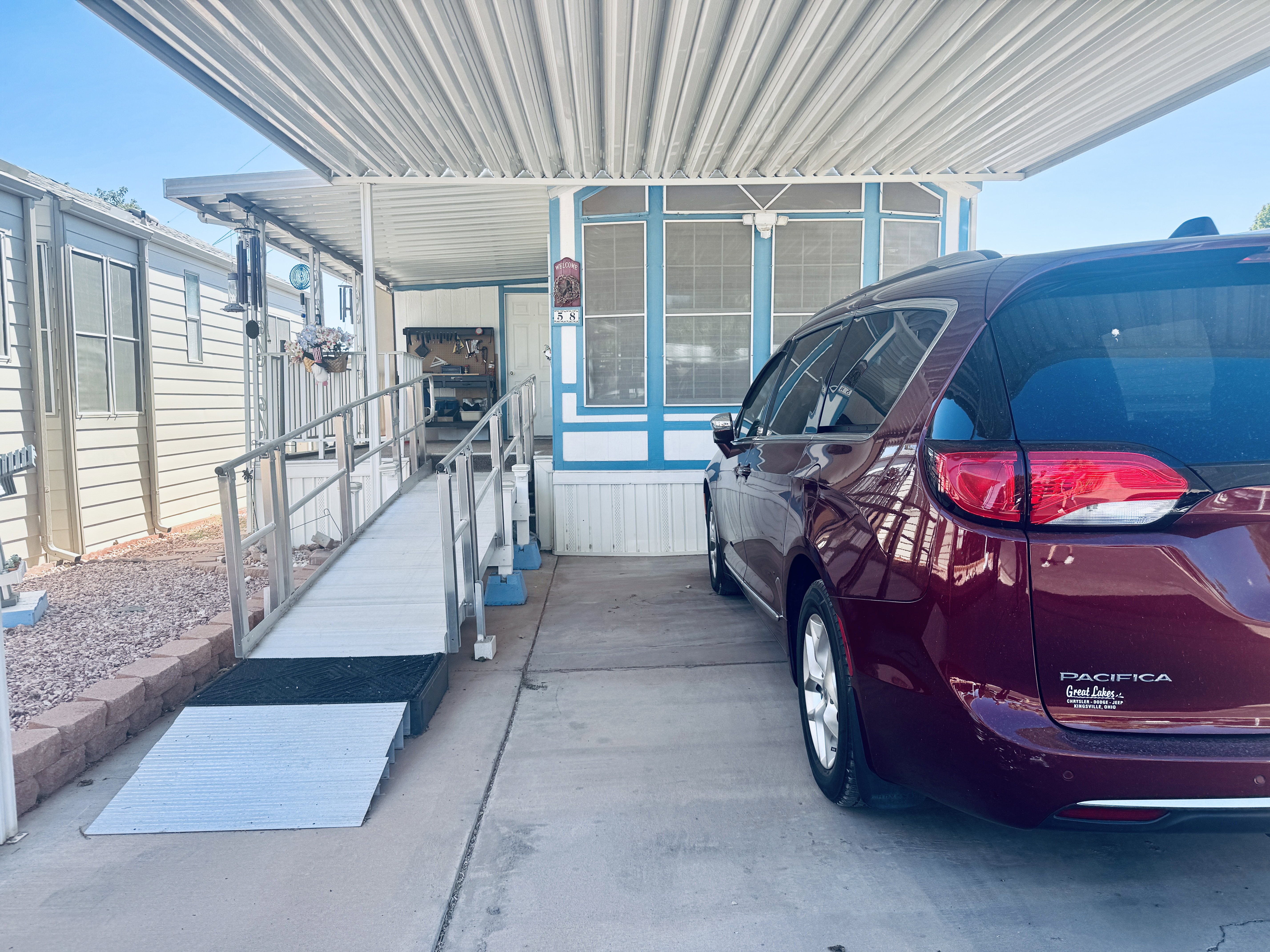Property exterior featuring a covered carport, concrete driveway, and a ramp entry with metal railings