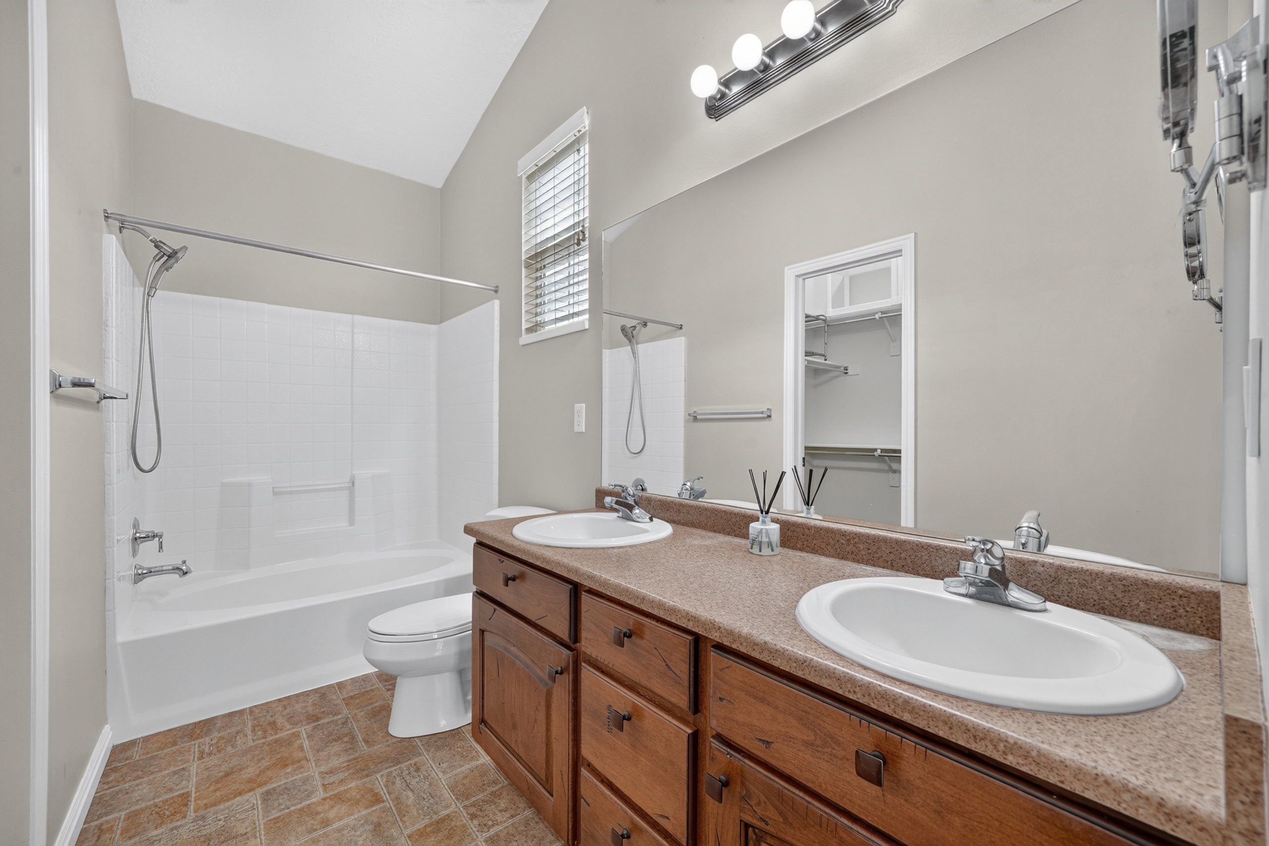 Bathroom with dual vanity, wood-finish cabinetry, built-in mirror, and overhead lighting