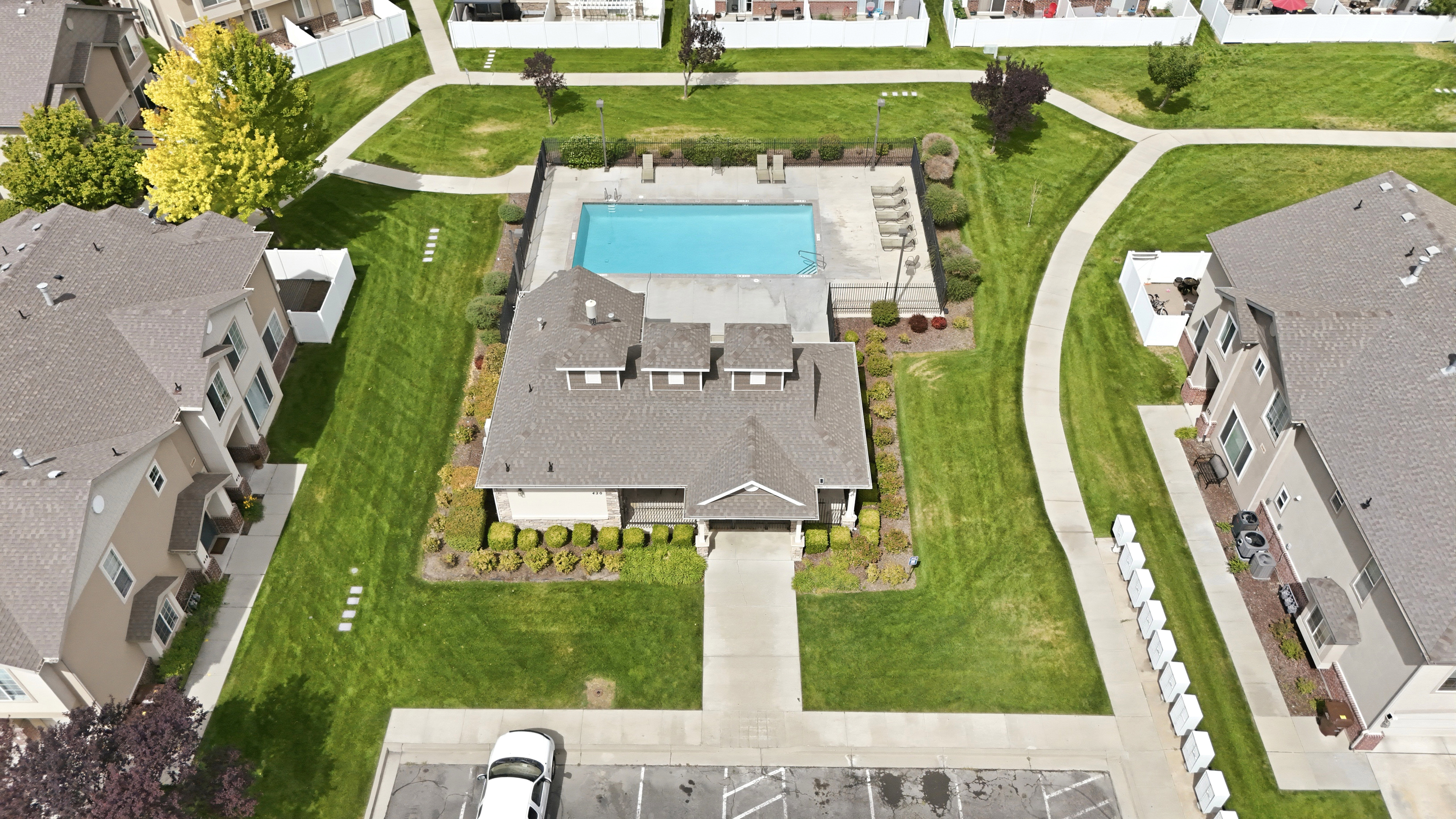 Community clubhouse featuring a rectangular swimming pool with integrated tanning ledge, surrounded by a paved deck with lounge seating