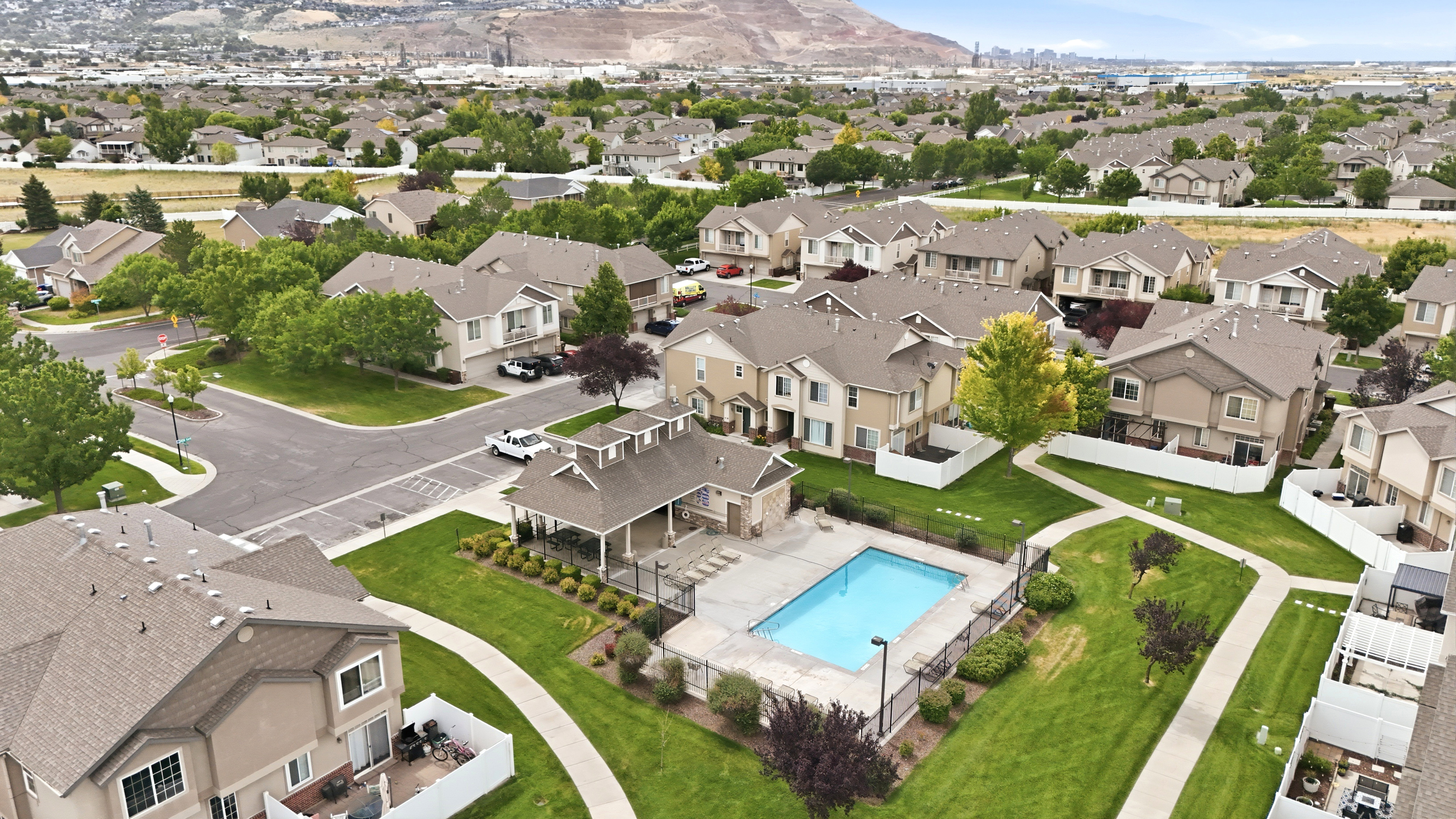Community pool with an adjacent covered patio, surrounded by manicured green spaces and paved walkways