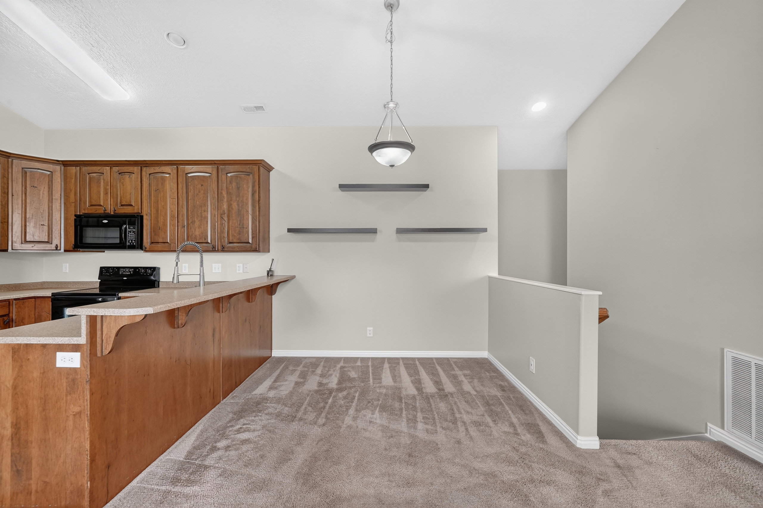 Kitchen featuring wood cabinetry, black appliances, a double basin sink, and a breakfast bar
