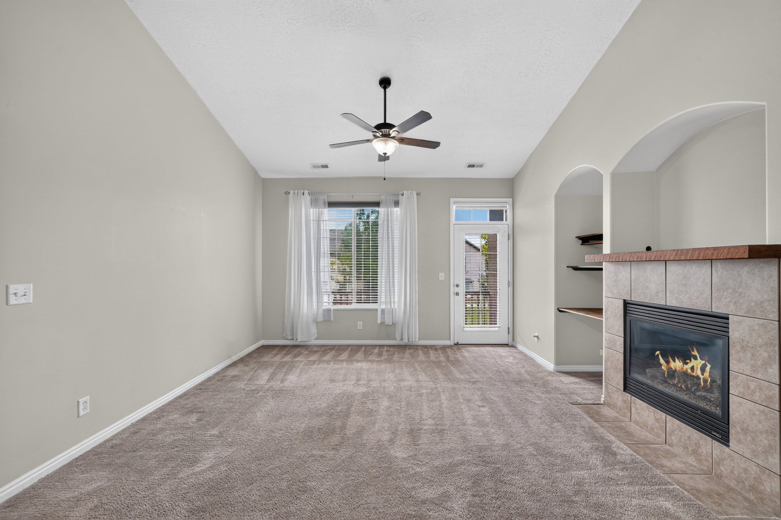 Spacious living area featuring a gas fireplace with a tile surround and wood mantel