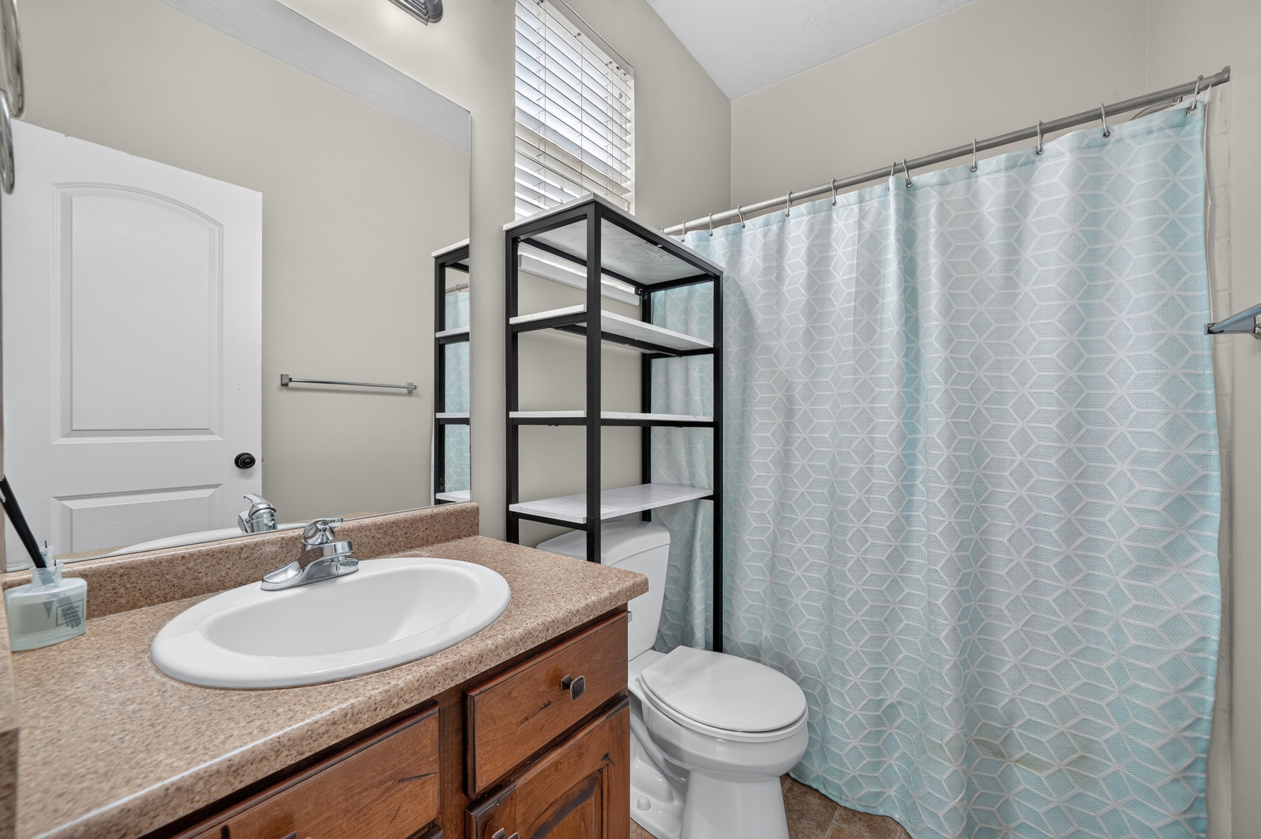 Full bathroom featuring a vanity with wood-finish cabinetry and a surface-mount sink, an extended mirror, and a combination shower/tub