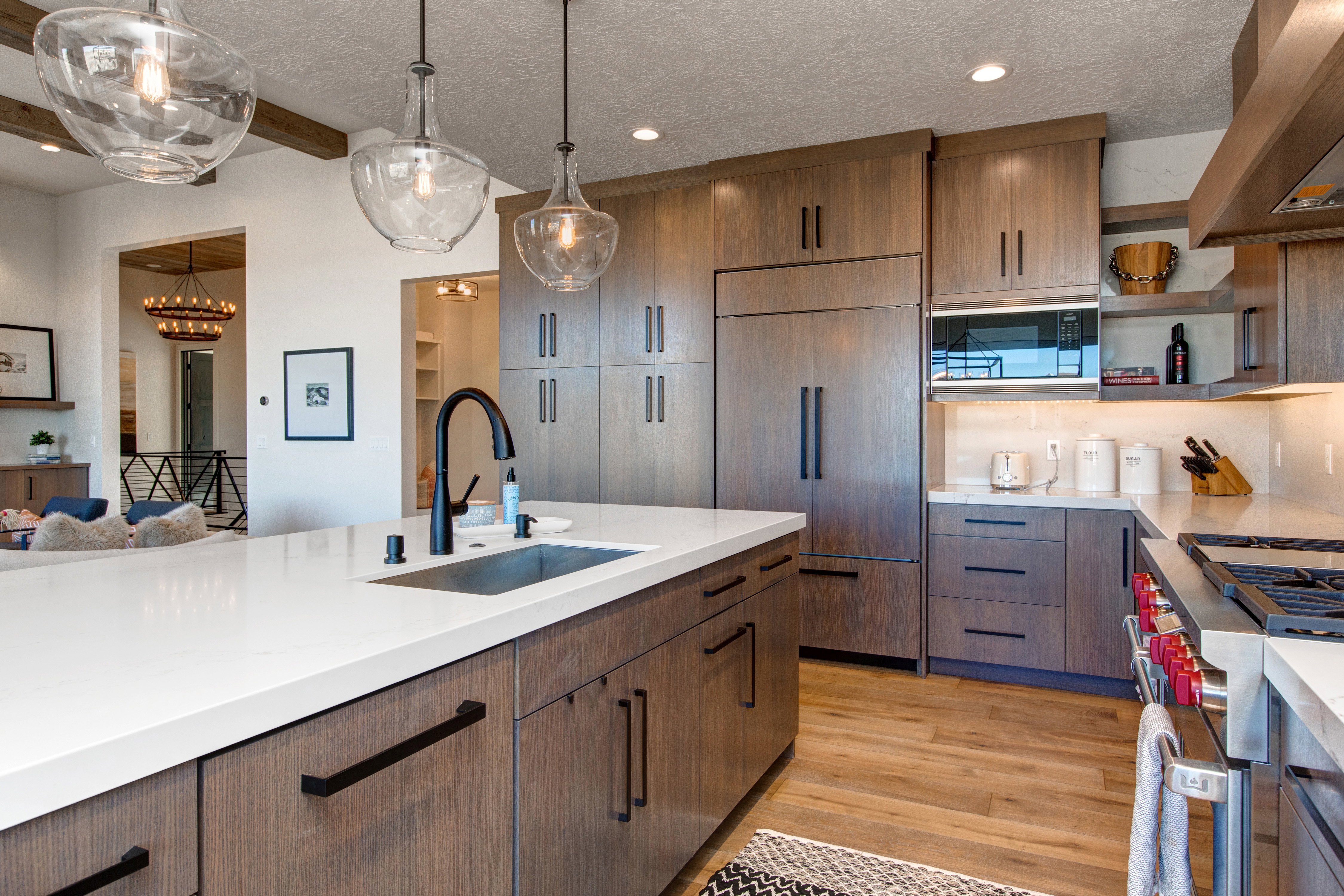 Kitchen featuring an expansive island with a stainless steel sink and matte black faucet, wood-finish cabinetry, stainless steel appliances, and a gas range