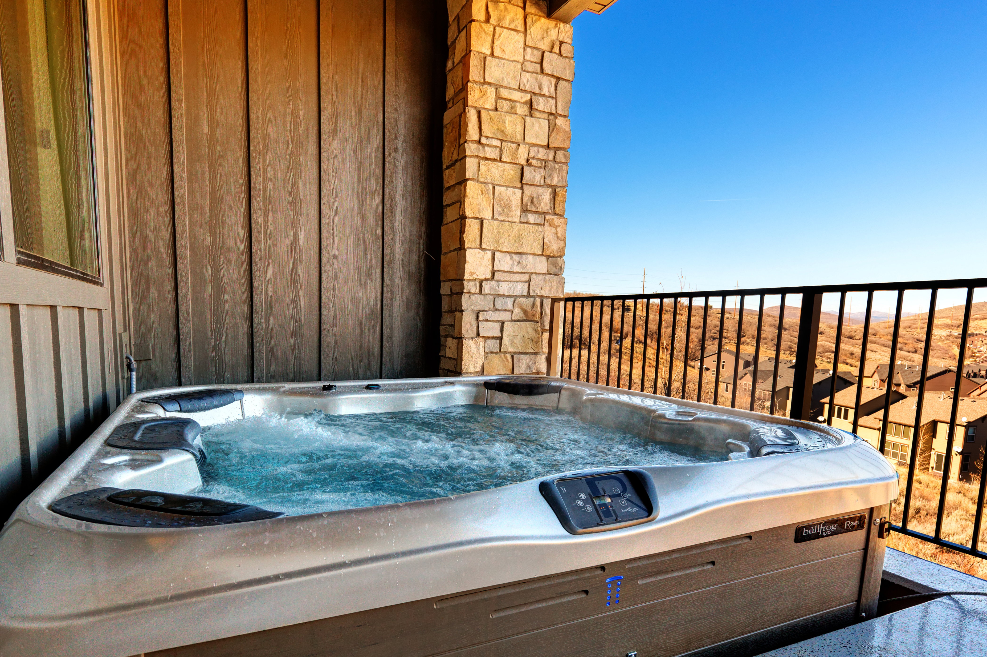 Outdoor hot tub on a stone-clad balcony with a metal railing