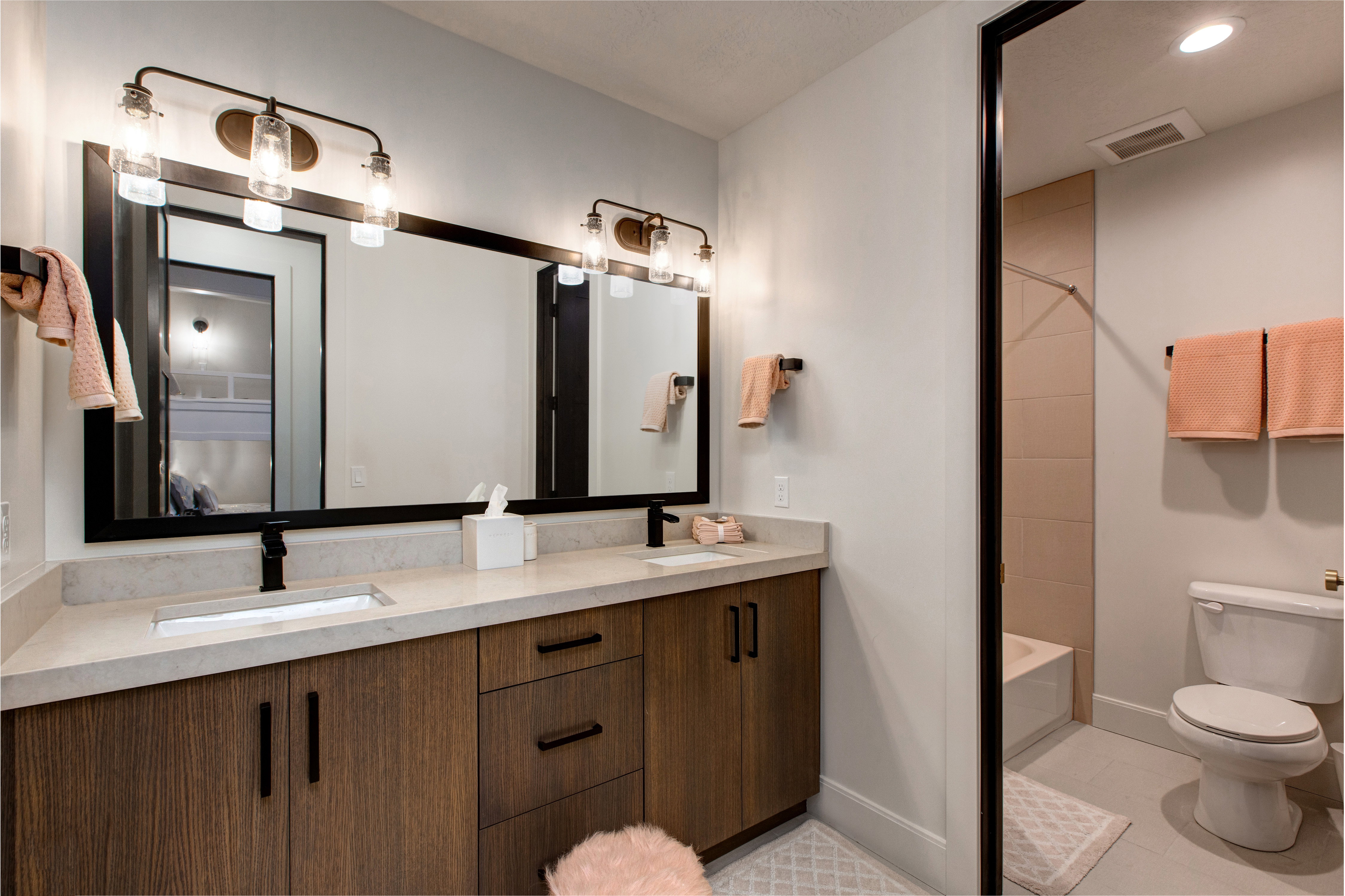 Dual vanity with wood-finish cabinetry, light-toned countertop, and undermount sinks