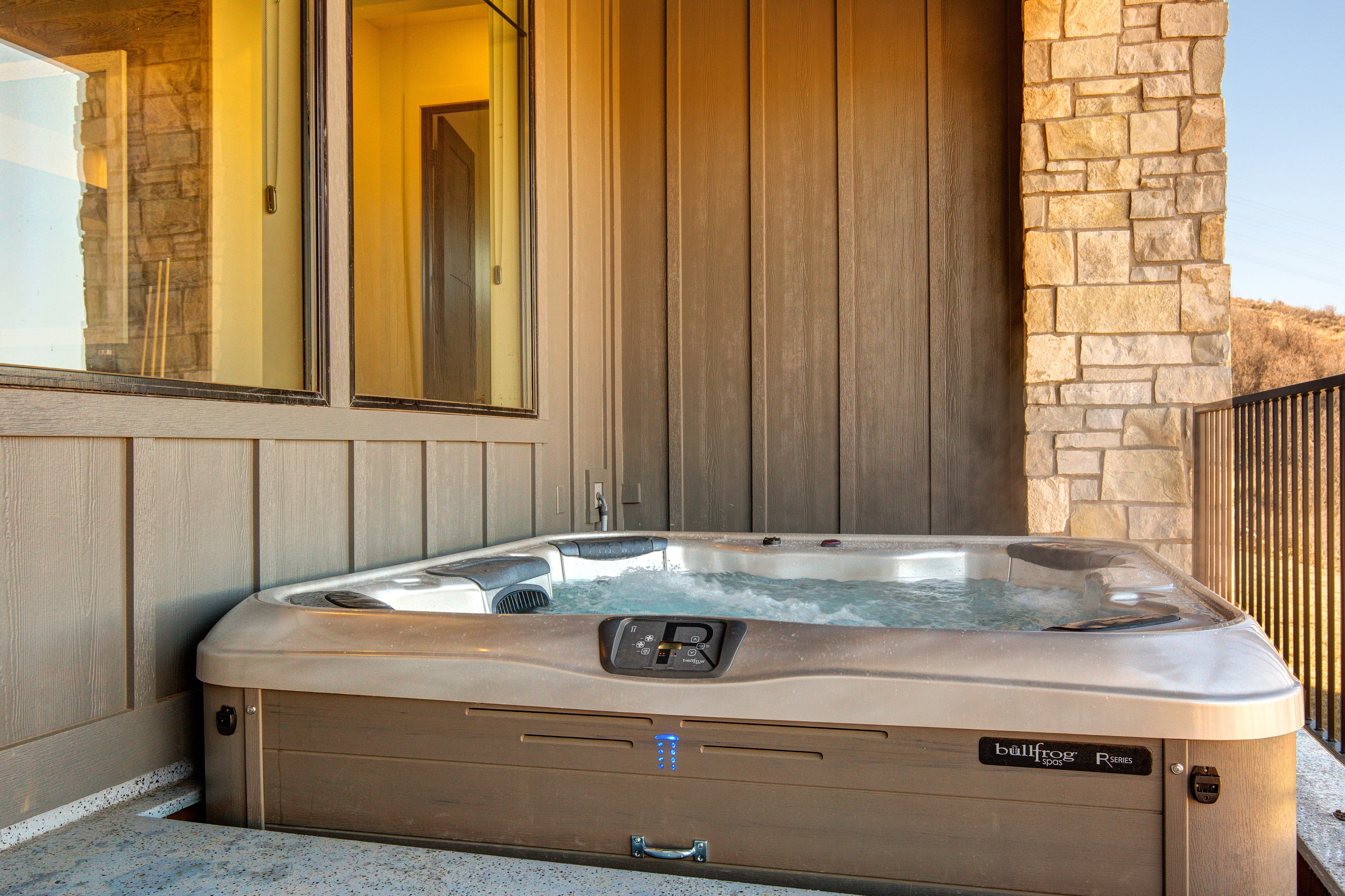 Outdoor hot tub featuring bubbling water and a light tan exterior