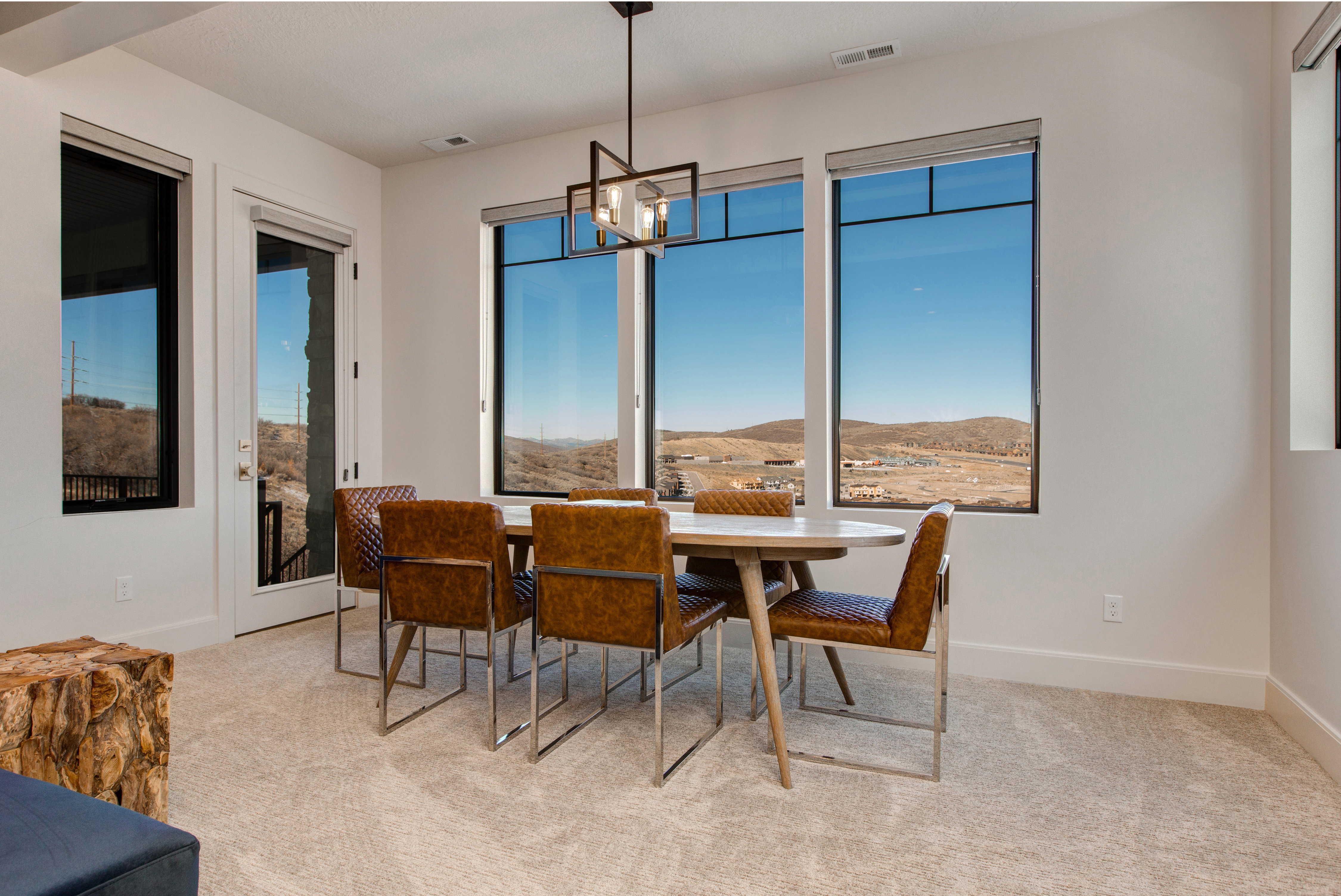 Dining area featuring a modern linear chandelier, an exterior glass door, and large windows with integrated blinds