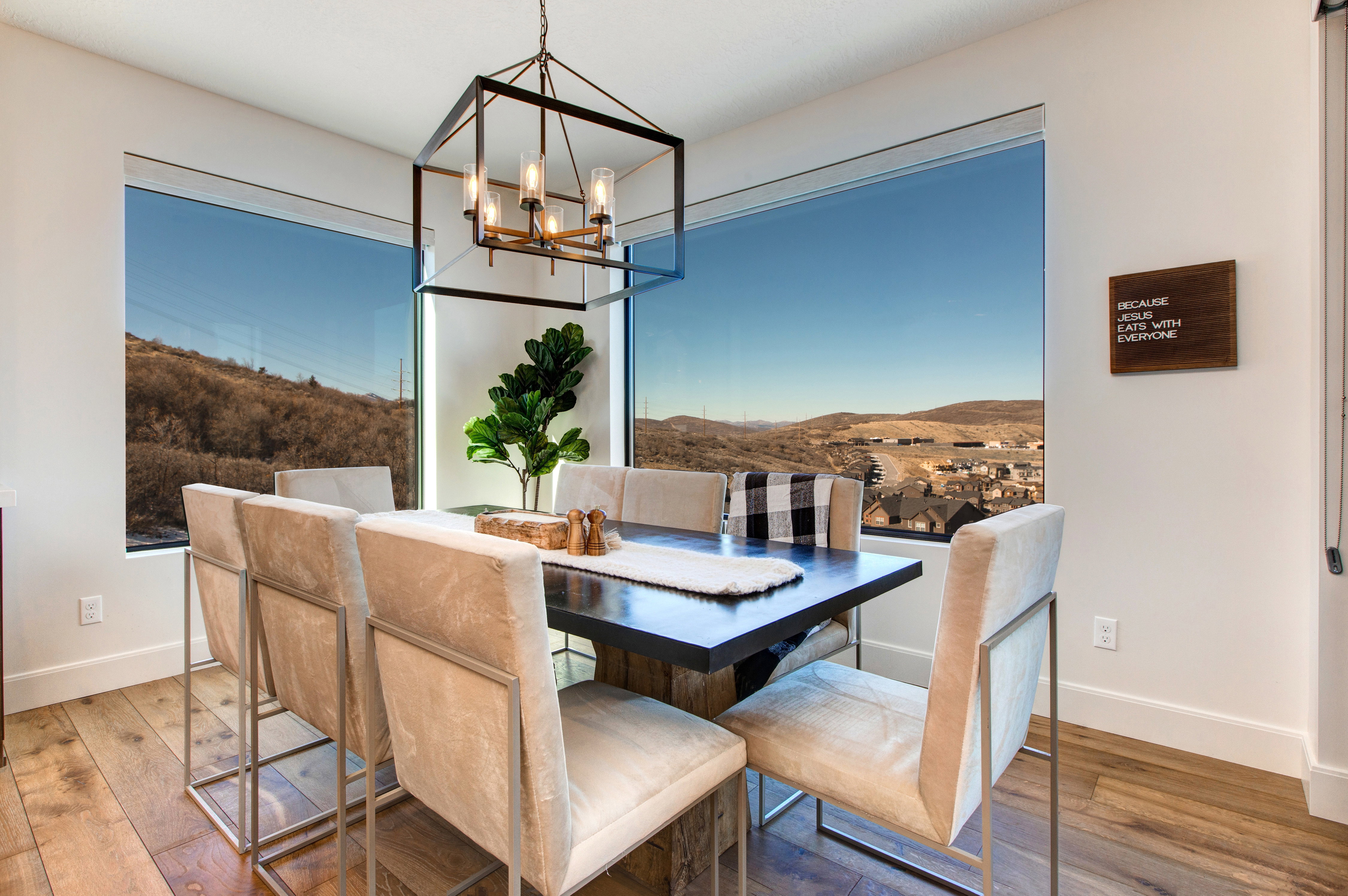 Dining area featuring expansive windows, wood-finish flooring, and a contemporary linear chandelier with a metal frame
