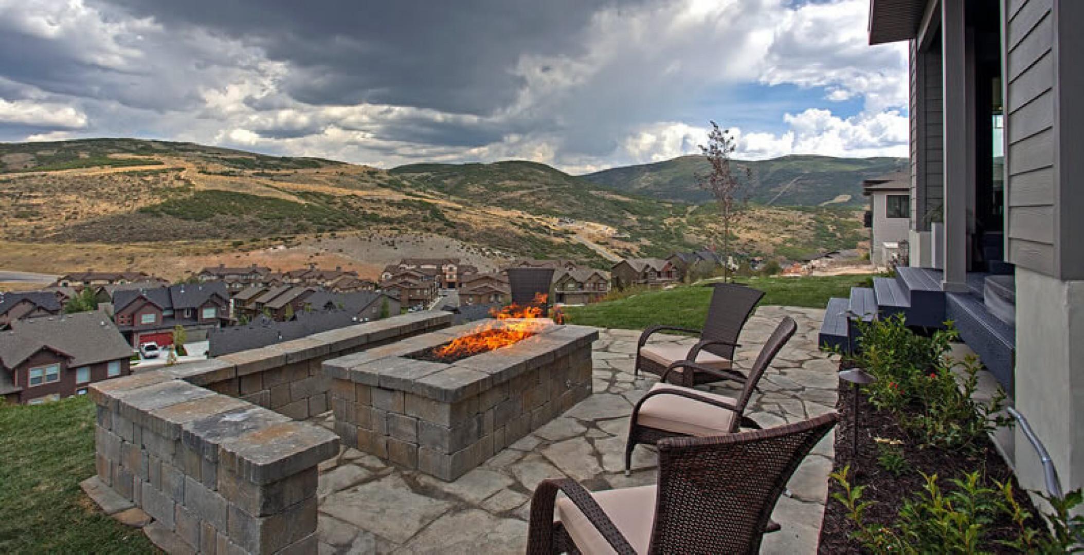 Expansive flagstone patio featuring a built-in stone fire pit and retaining wall