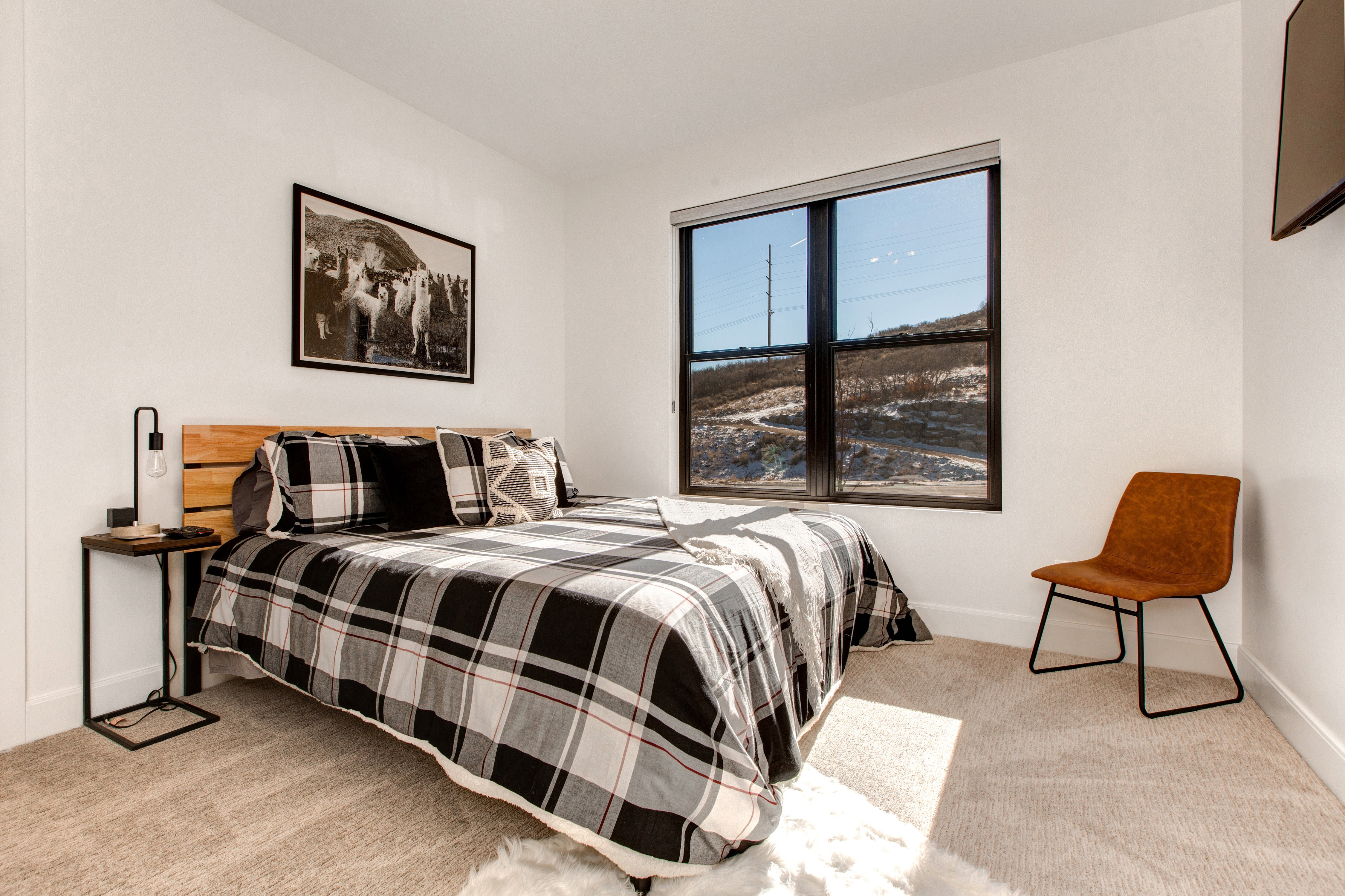 Bedroom featuring a large picture window, neutral wall paint, and light-toned carpet flooring