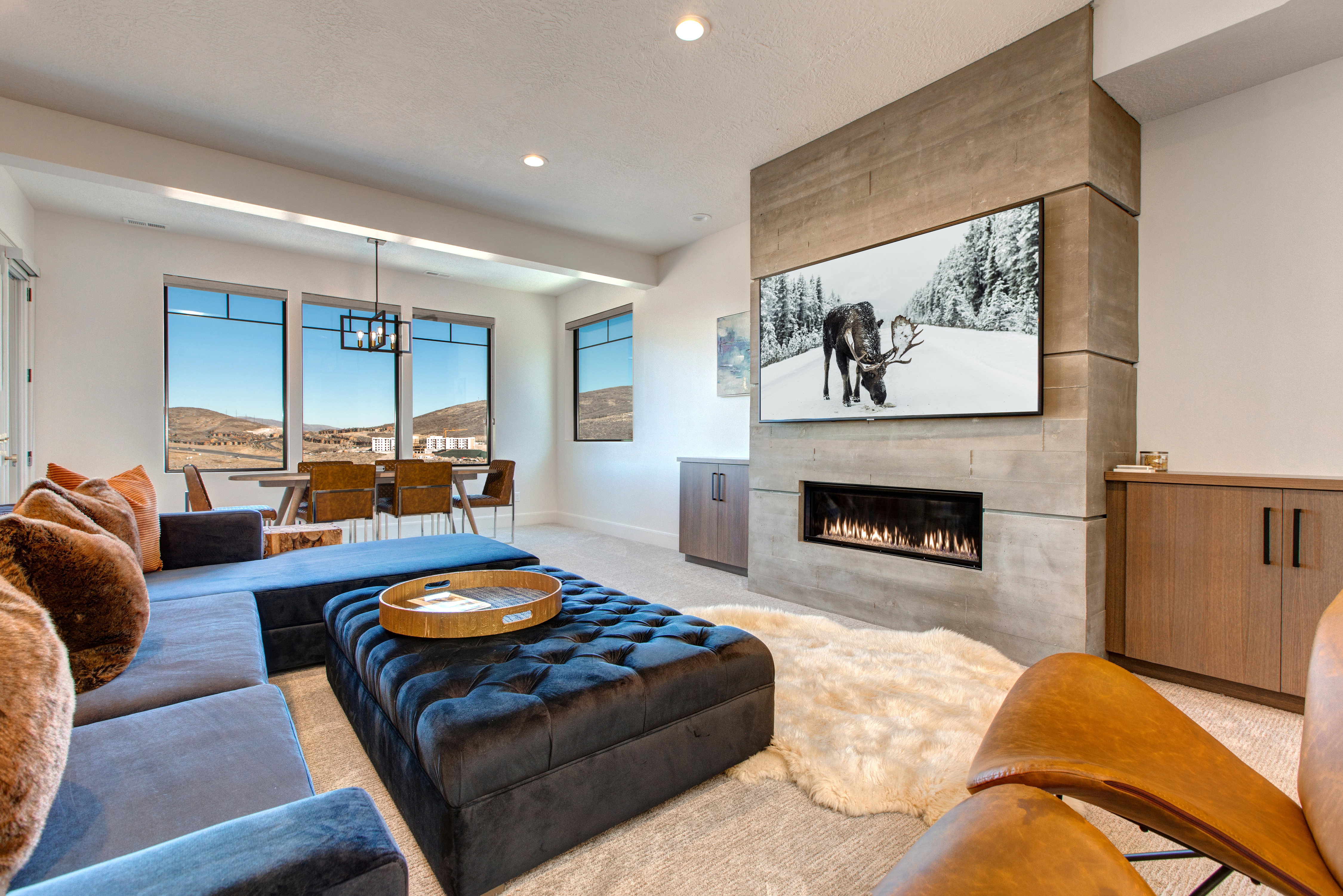 Spacious living area featuring a modern linear fireplace with a textured surround, integrated television, and built-in wood-finish cabinetry