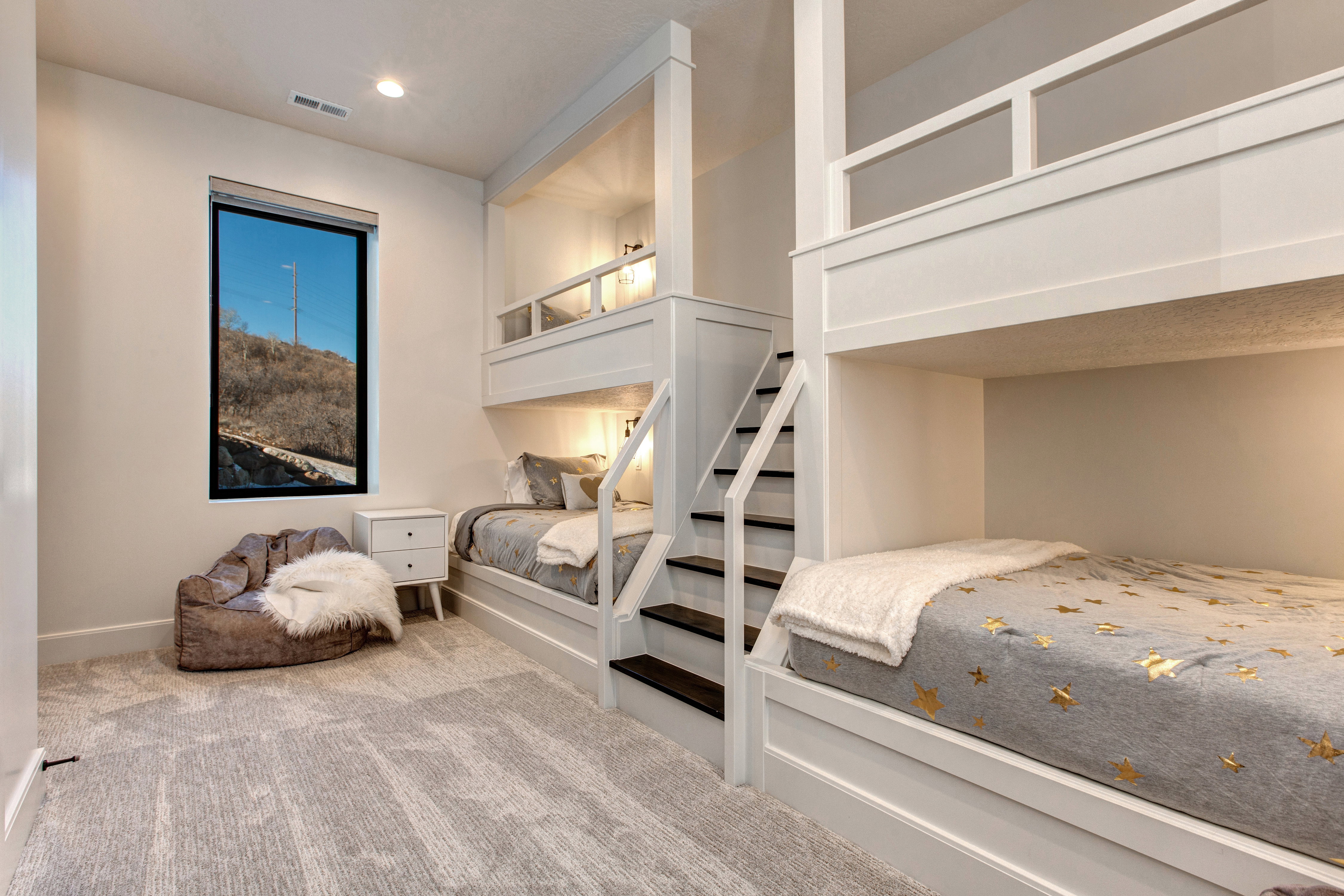 Built-in bunk beds featuring integrated stairs, recessed lighting, and individual sleeping nooks