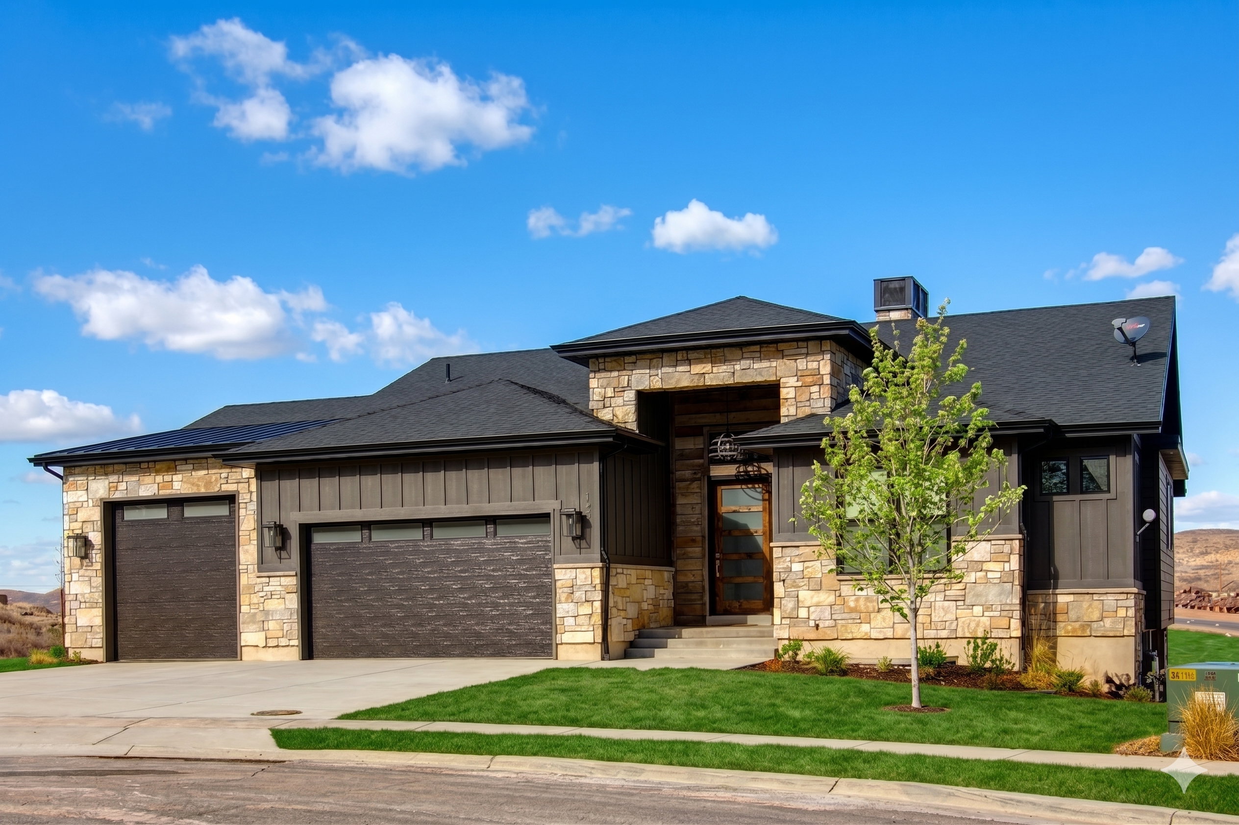 Contemporary residence featuring stone and board-and-batten siding, a dark asphalt shingle roof, solar panels, and a two-car garage with textured doors