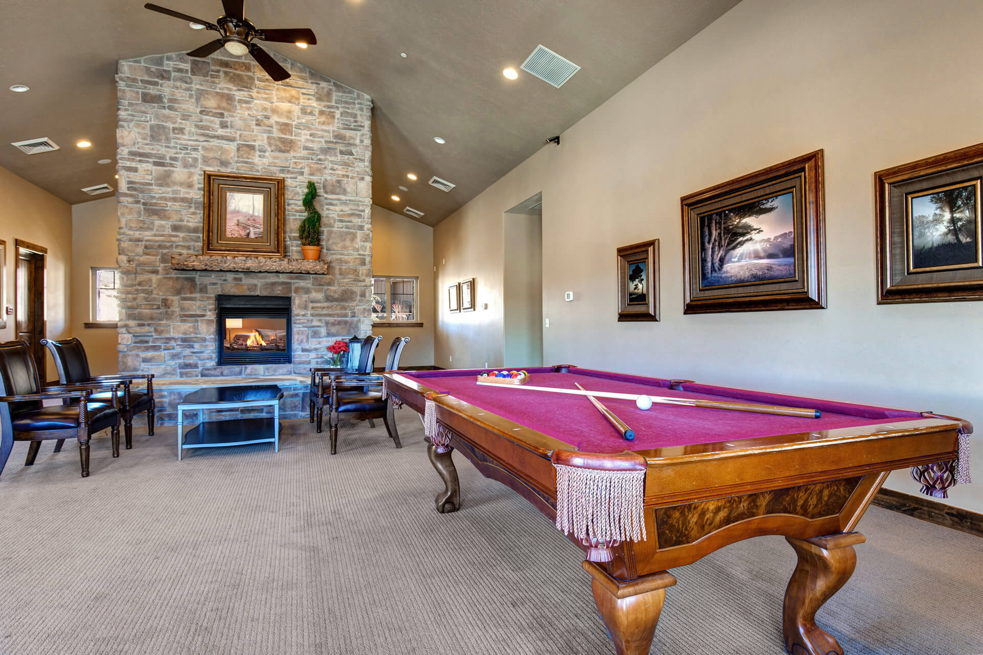 Spacious common area featuring a stone fireplace with hearth, vaulted ceiling, recessed lighting, and ceiling fan