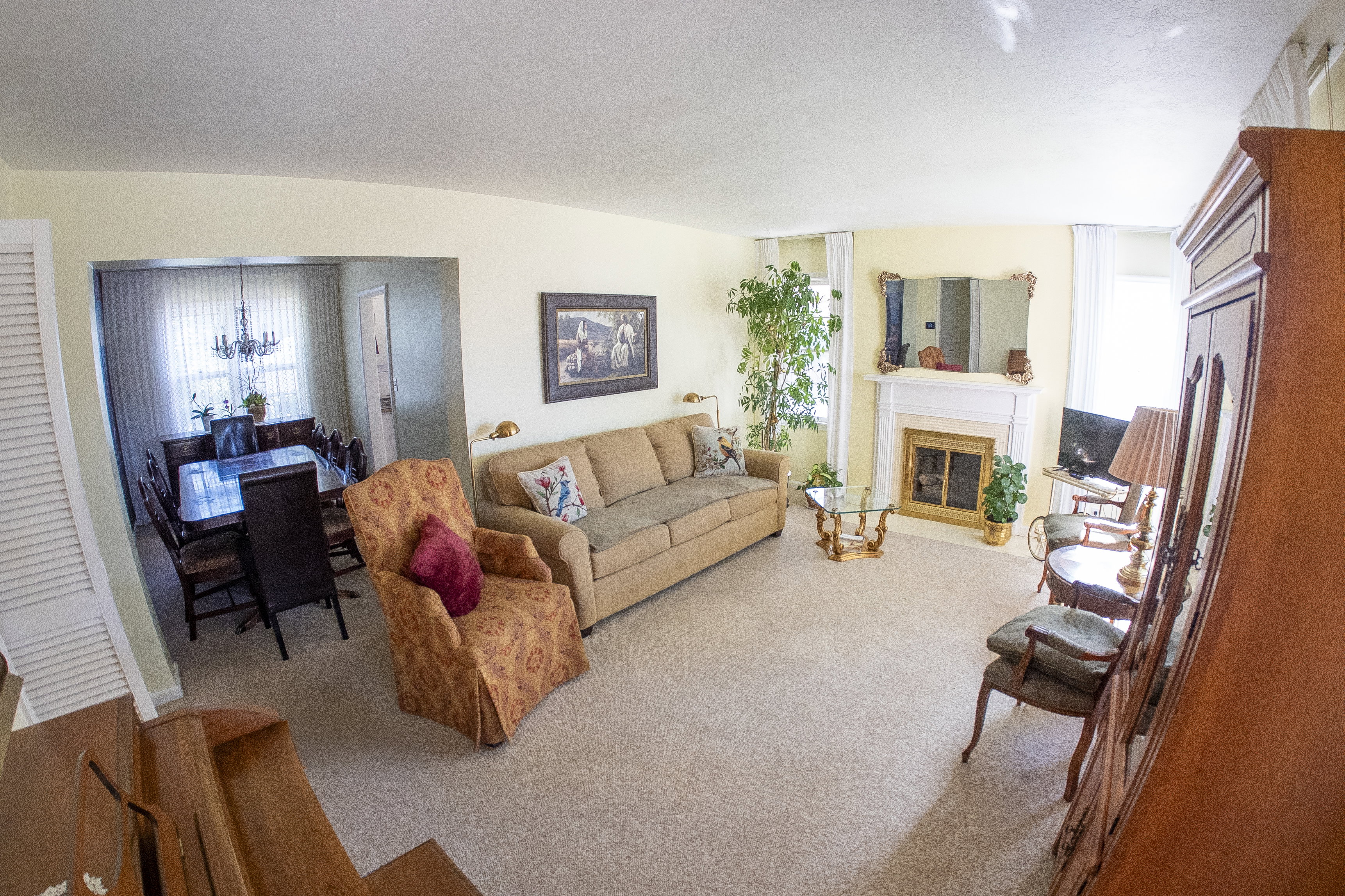 Carpeted living room featuring a white fireplace surround with an integrated mantel and hearth