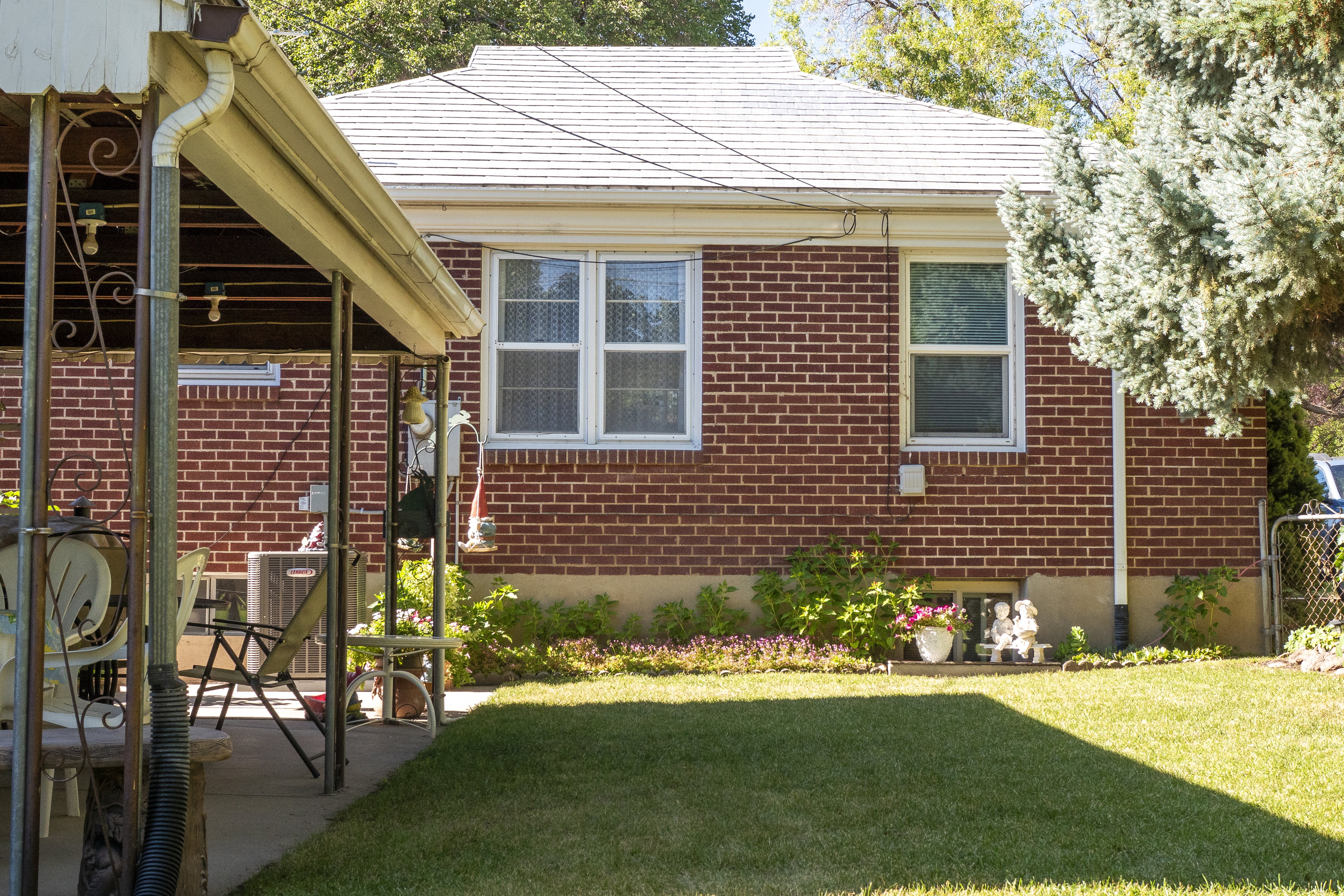 Brick exterior with a white shingle roof, featuring multiple windows and a covered patio area