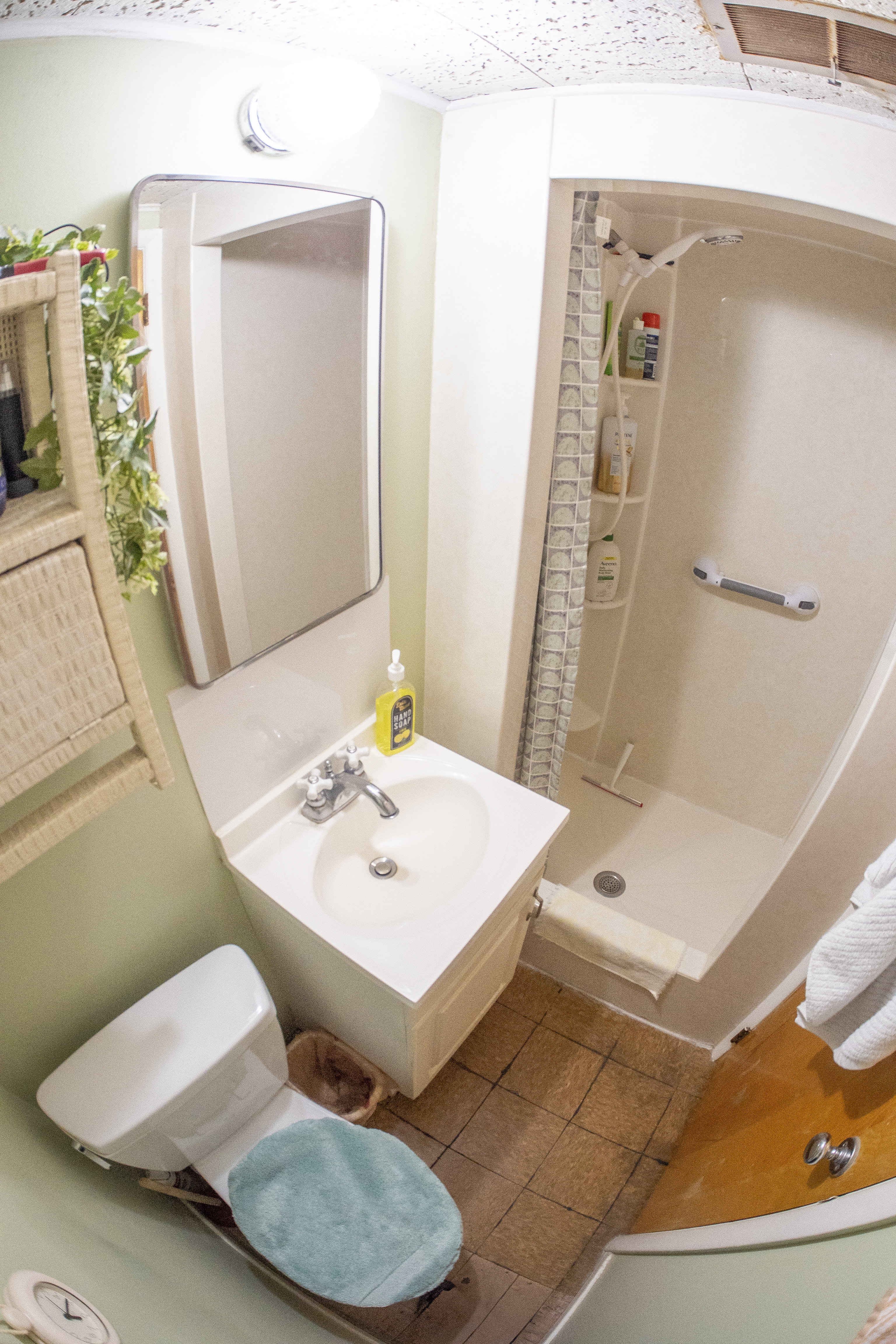 Compact bathroom featuring a white vanity with integrated sink, chrome faucet, and mirrored cabinet