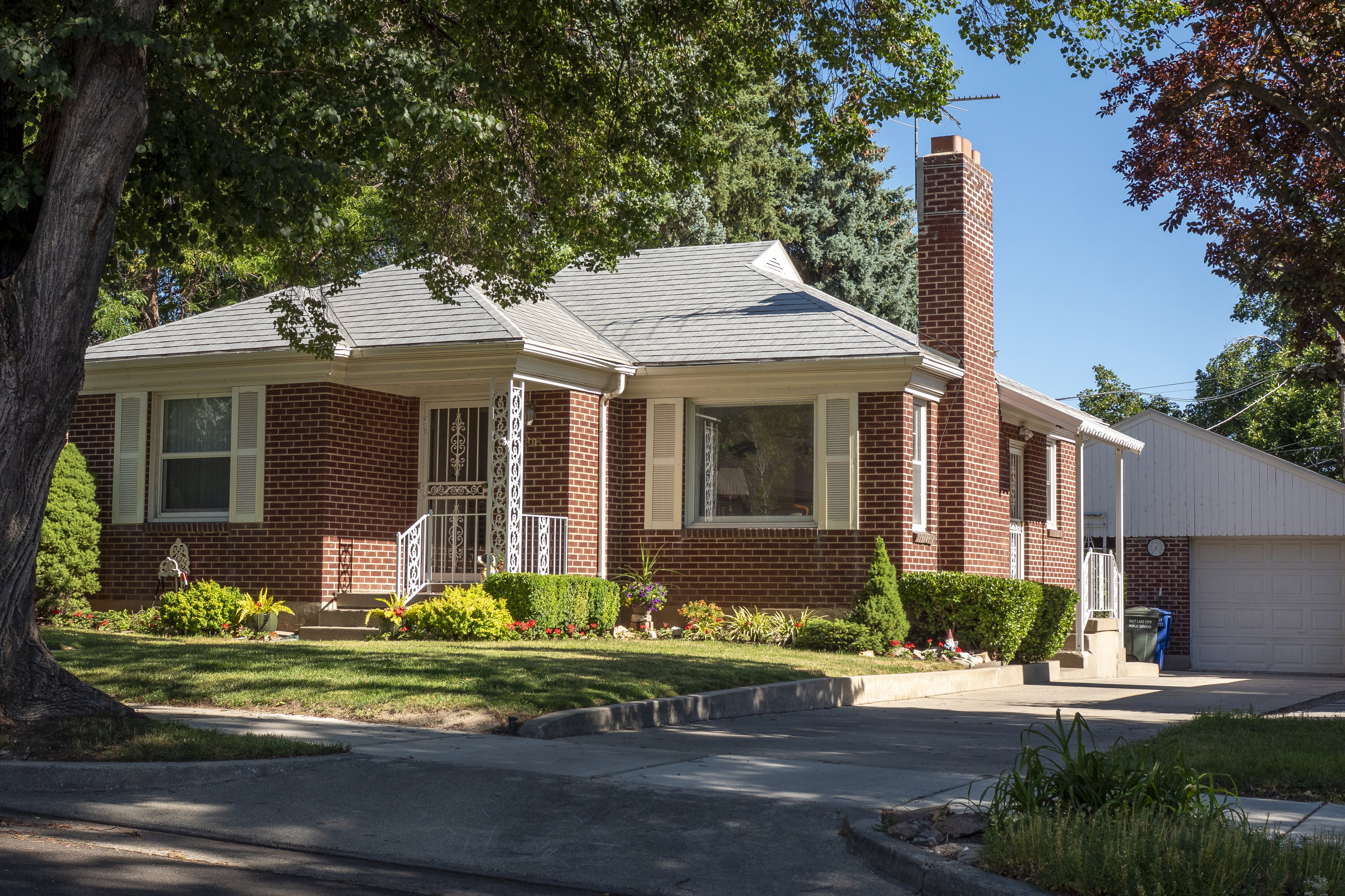 Brick exterior residence featuring a grey shingle roof and a prominent brick chimney