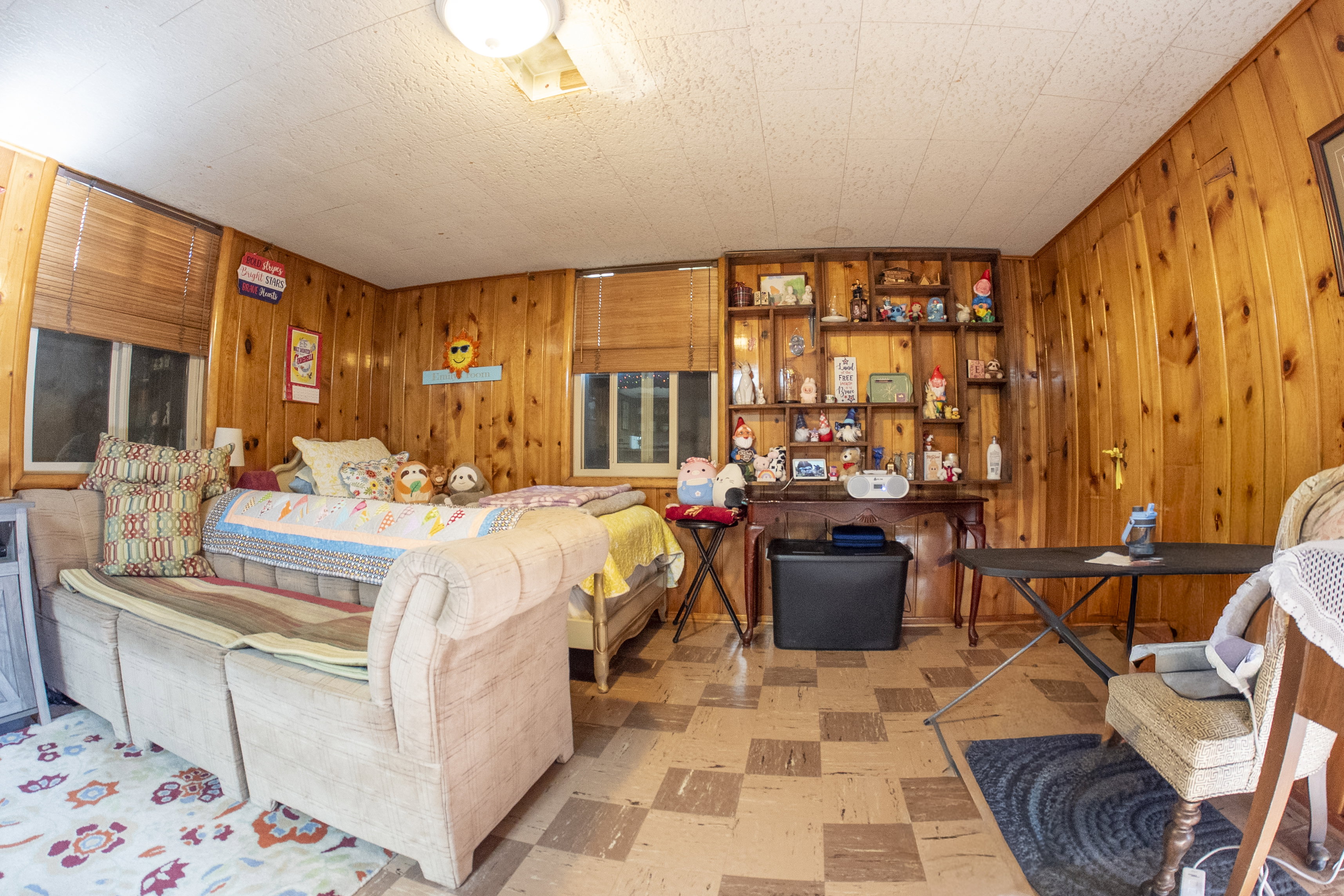 Room featuring wood-paneled walls, ceiling-mounted lighting, and a patterned flooring