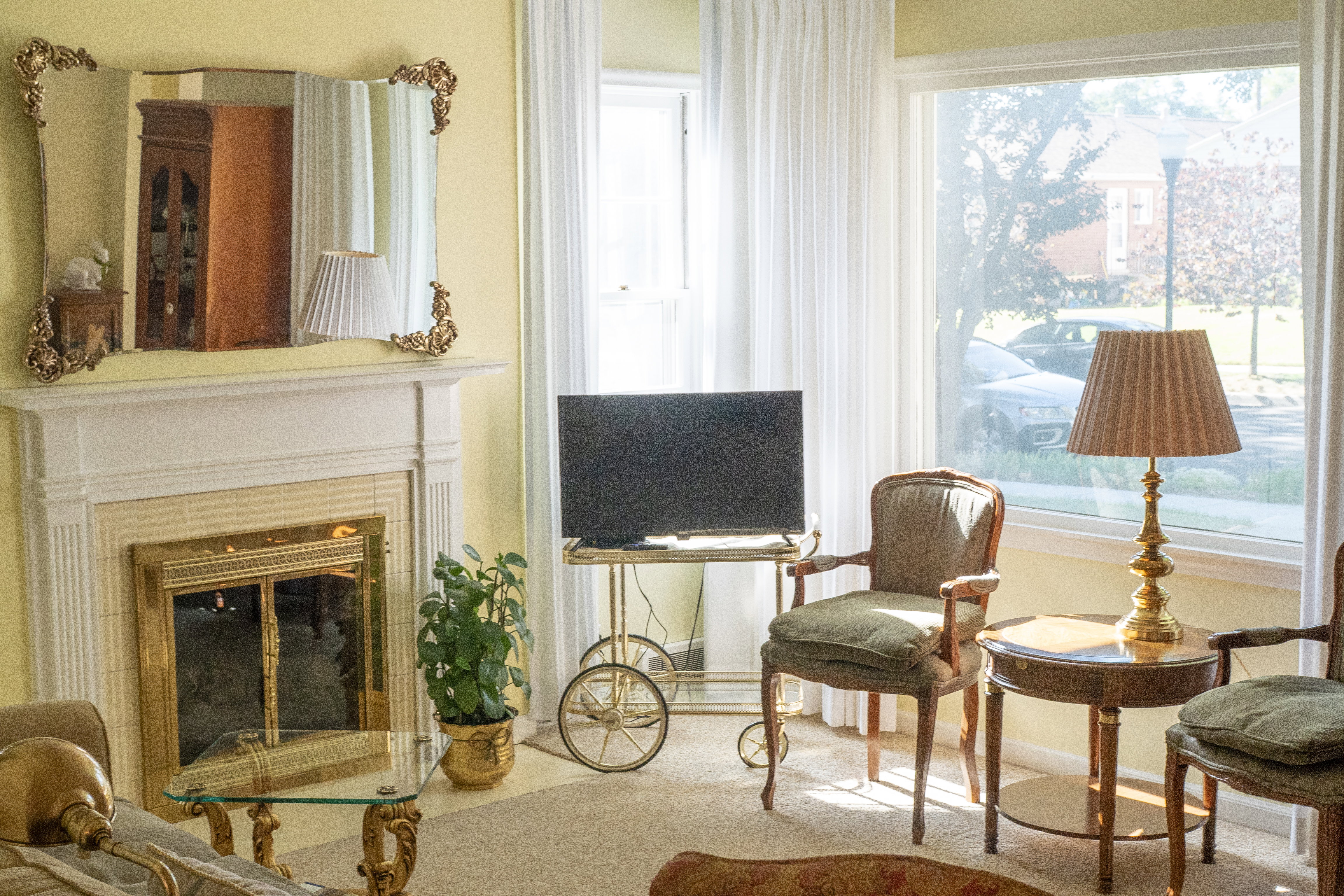 Living area featuring a fireplace with a brass-trimmed insert, a mantel, and large windows