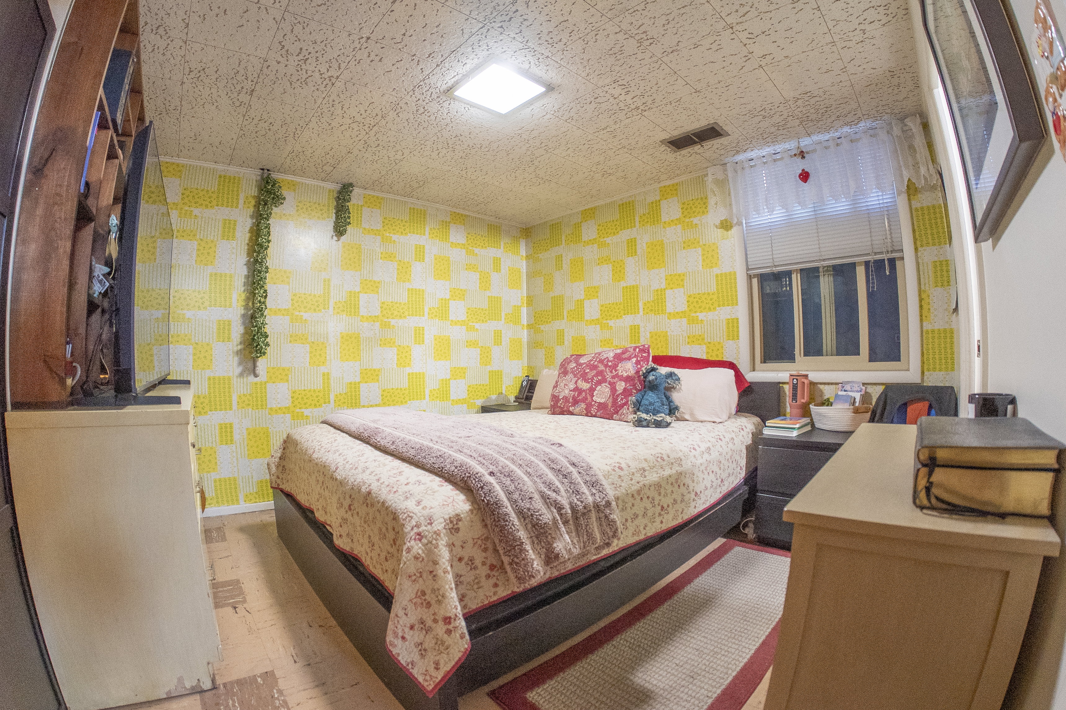 Room featuring patterned yellow and white walls, textured ceiling, and a single window with blinds