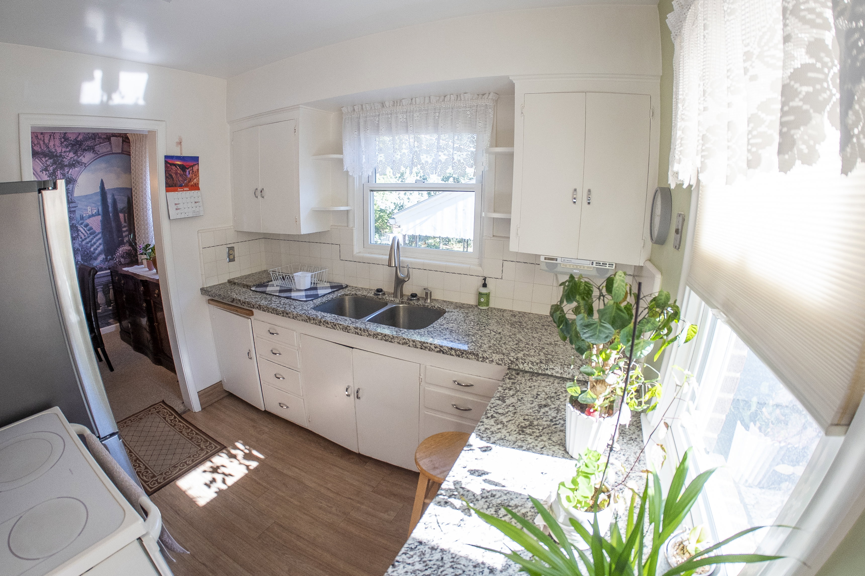 Kitchen featuring white cabinetry, wood-finish flooring, a double basin sink with a high-arc faucet, and light-toned speckled countertops