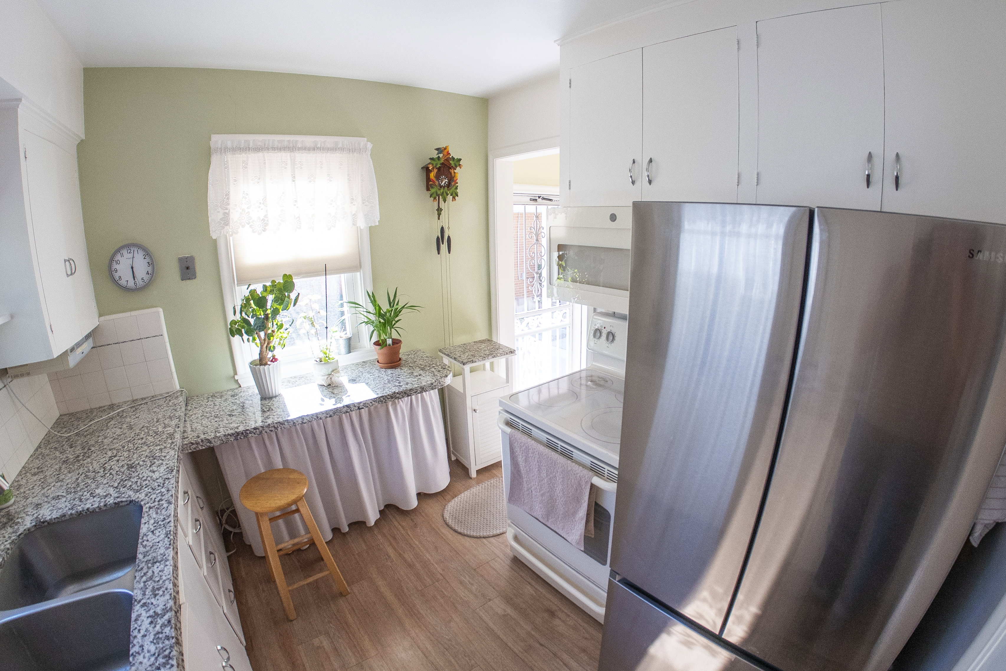 Kitchen featuring wood-finish flooring, white cabinetry, granite-finish countertops, stainless steel refrigerator, and a double basin sink