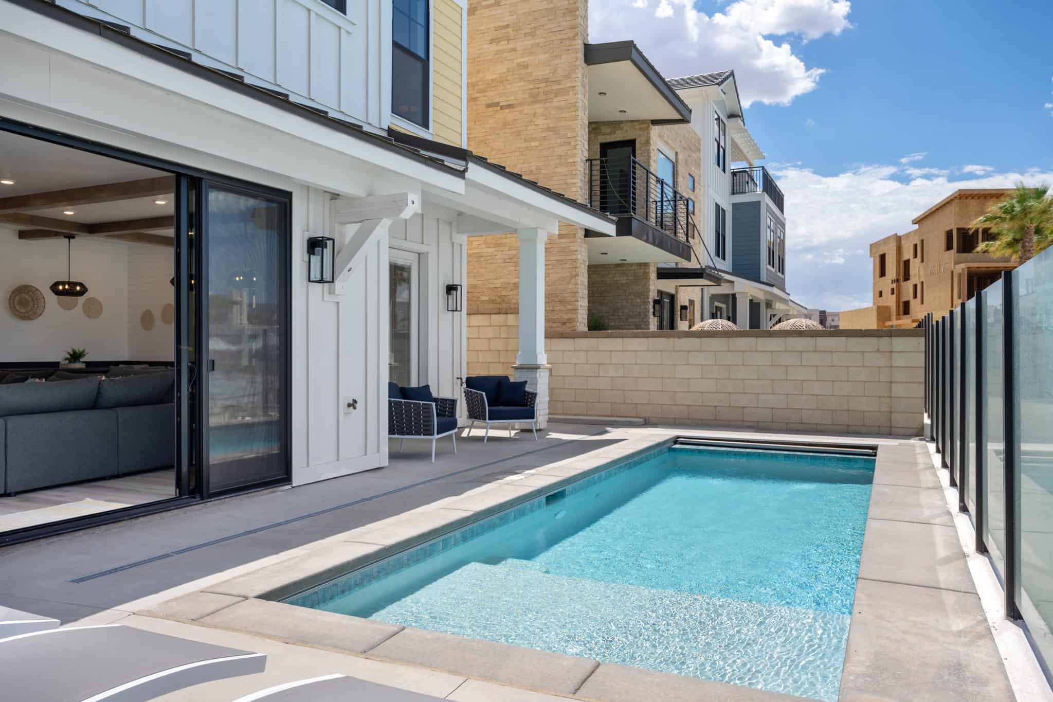 Outdoor pool with integrated steps, surrounded by a concrete patio and a glass panel fence