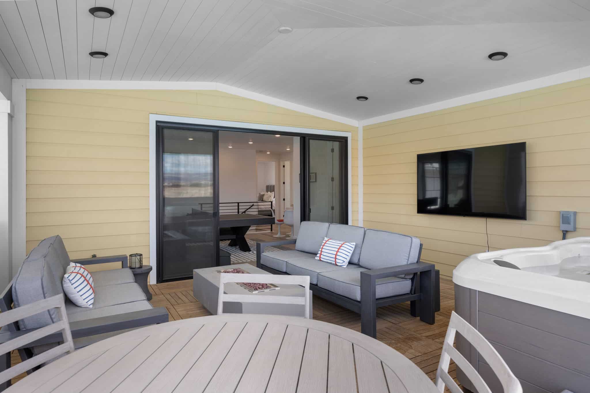 Covered patio featuring a hot tub, mounted television, and wood-finish flooring