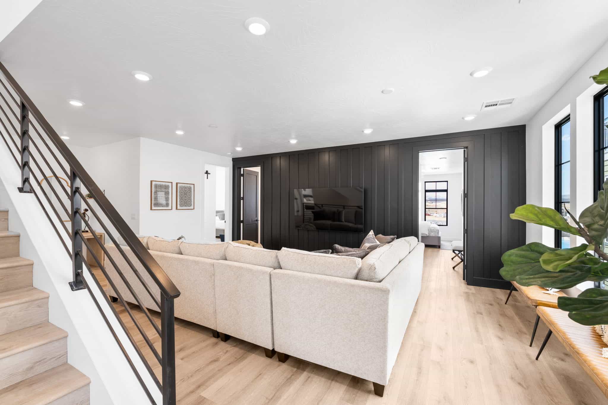 Open-concept living space with light wood-finish flooring, recessed lighting, and a contemporary dark wood-paneled accent wall