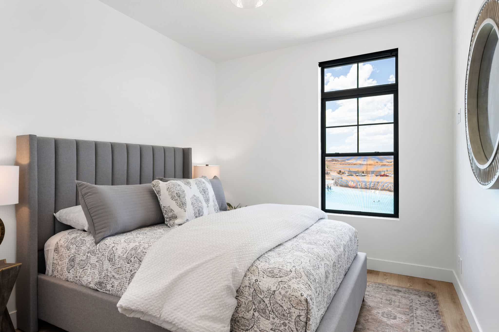 Light-filled room featuring a large black-framed window, white walls, and wood-finish flooring