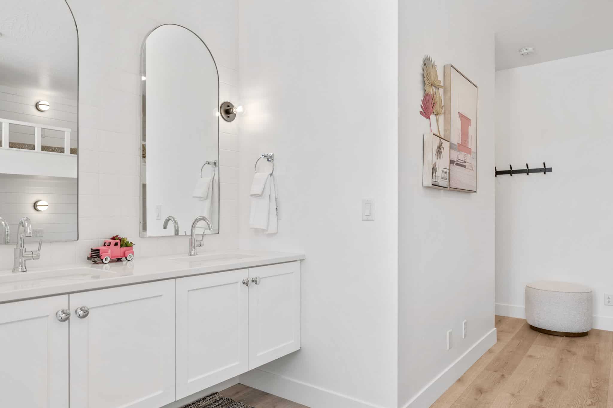 Dual vanity with white cabinetry, polished chrome hardware, and arched mirrors