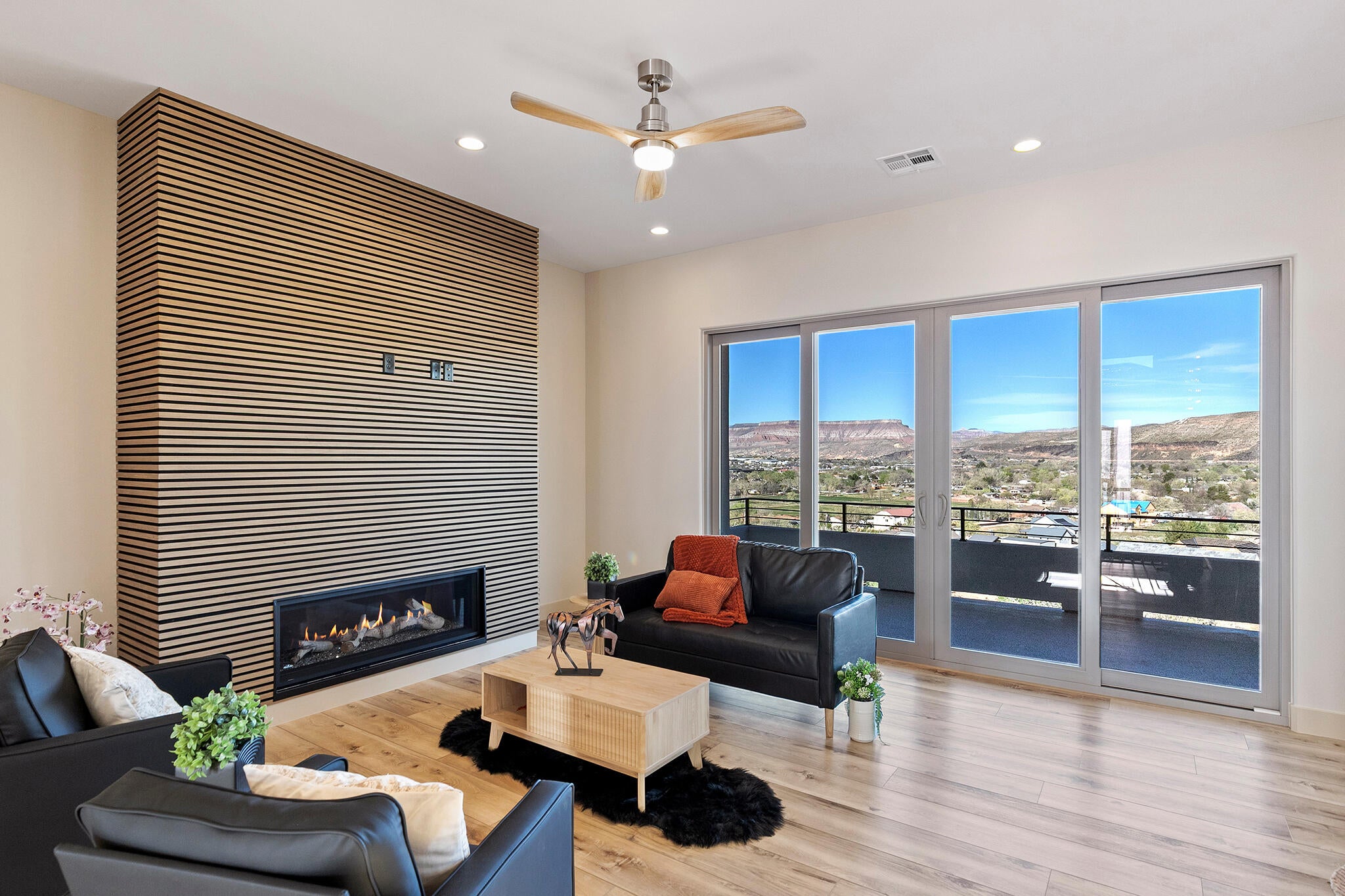 Spacious living area featuring a linear gas fireplace set into a slatted wood accent wall, wood-finish flooring, and recessed lighting