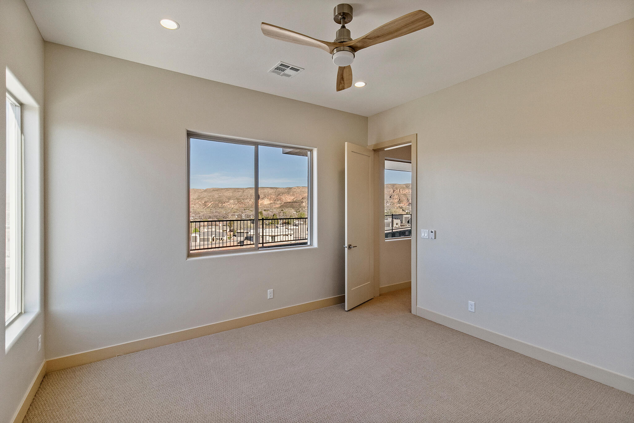 Carpeted room featuring a ceiling fan with light, recessed lighting, and expansive windows showcasing a mountain backdrop